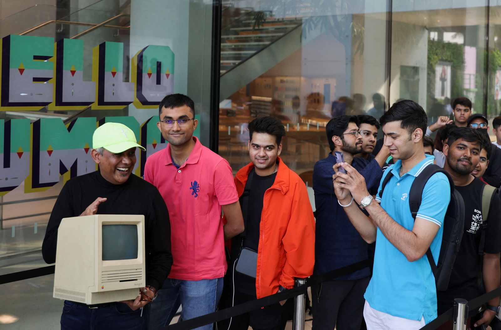 An Apple fan takes a photo of Sajid Moinuddin as he poses with a Macintosh SE computer while waiting in a queue outside India's first Apple retail store, on the day of its opening in Mumbai, India, April 18, 2023. REUTERS/Francis Mascarenhas