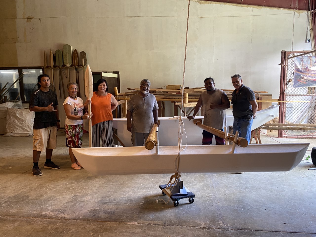 Kuen Hee Han, third left, with Master Navigator Mario Benito, 500 Sails staff, and a volunteer. They are standing in front of a contemporary Chamorro canoe which was fabricated in Lower Base at the 500 Sails boatyard.