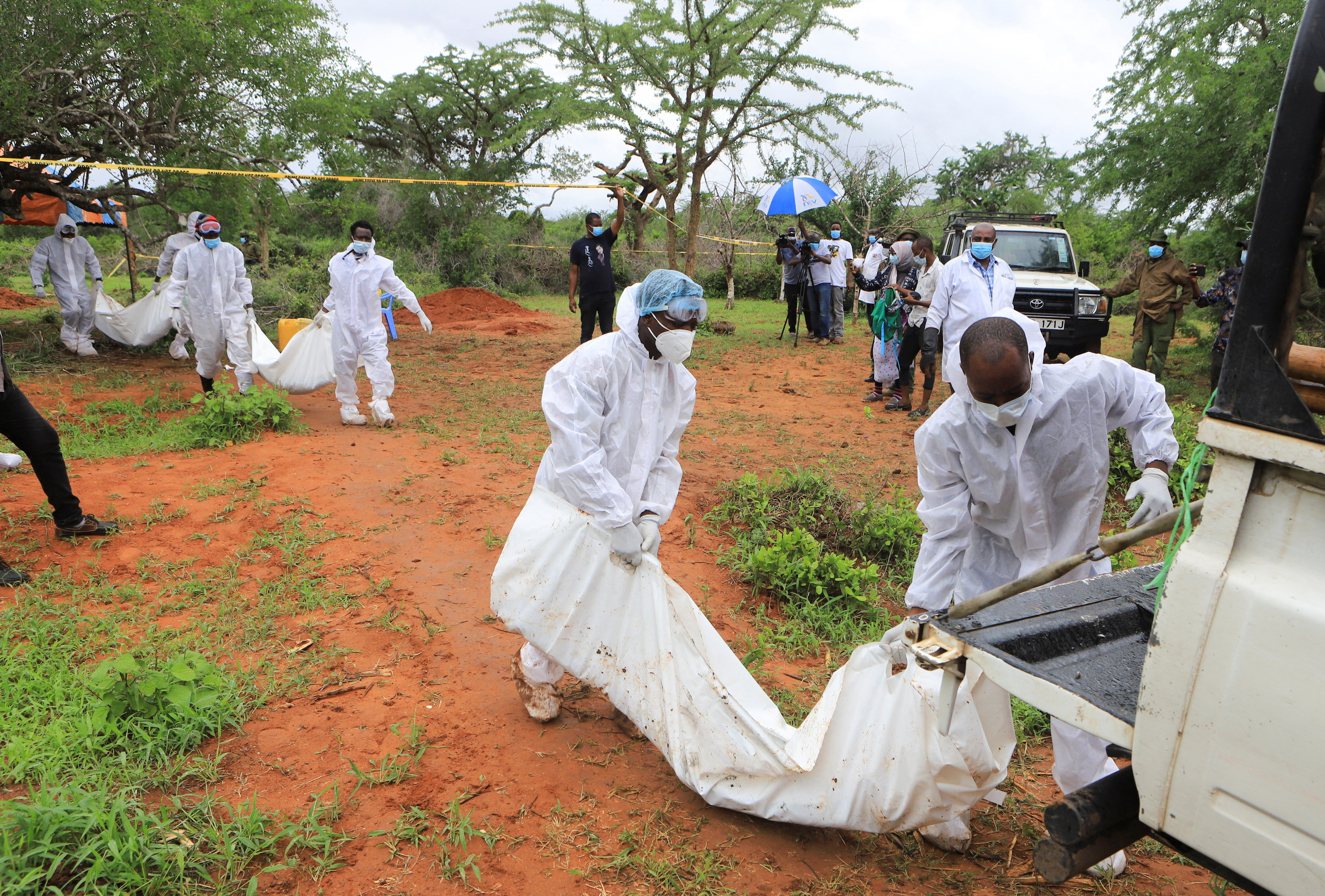 Forensic experts and homicide detectives carry the bodies of suspected members of a Christian cult named as Good News International Church, who believed they would go to heaven if they starved themselves to death, after their remains were exhumed from their graves in Shakahola forest of Kilifi county, Kenya April 22, 2023. REUTERS/Stringer