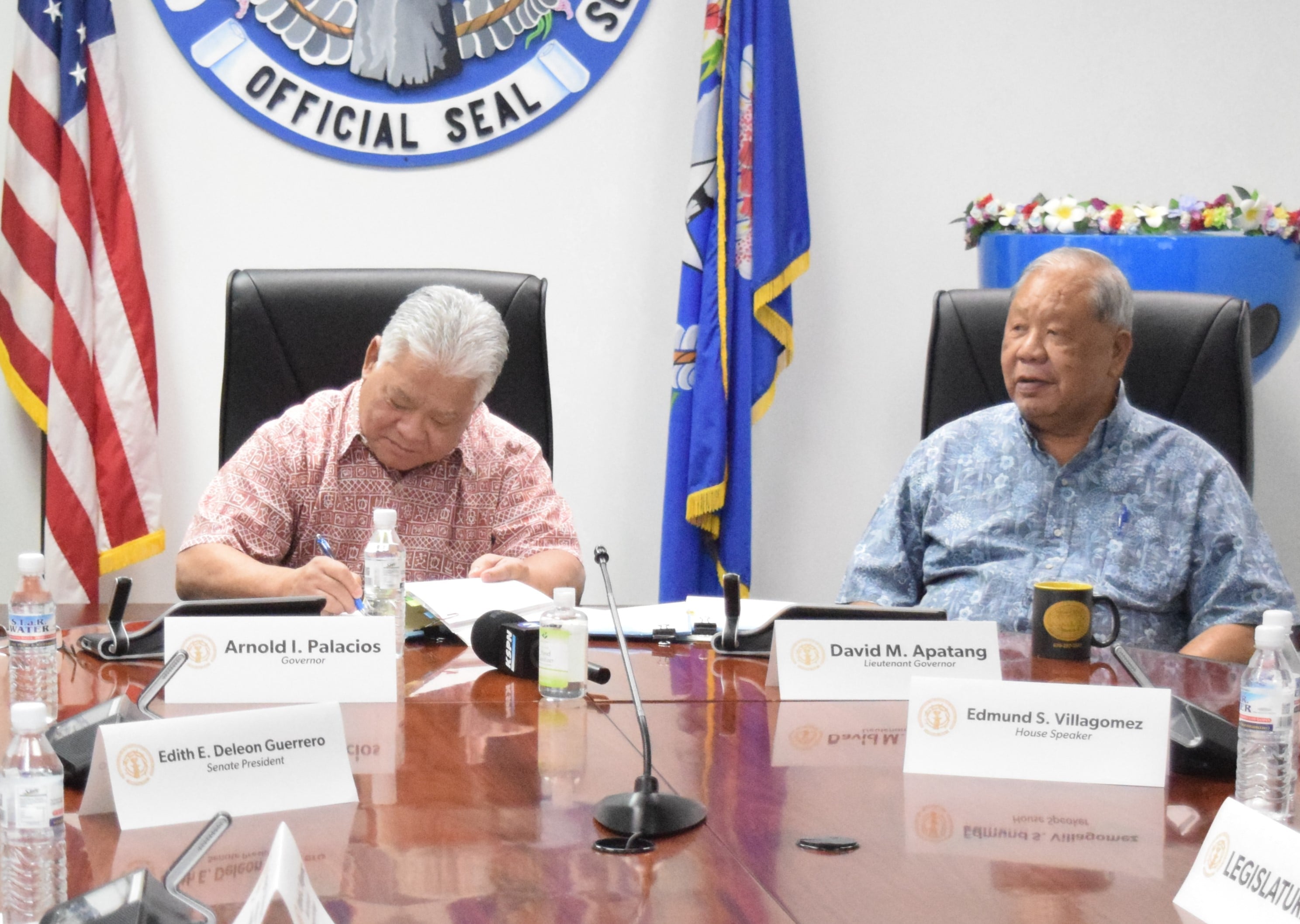 Gov. Arnold I. Palacios signs the revised fiscal year 2023 budget bill into law while Lt. Gov. David M. Apatang looks on Tuesday.