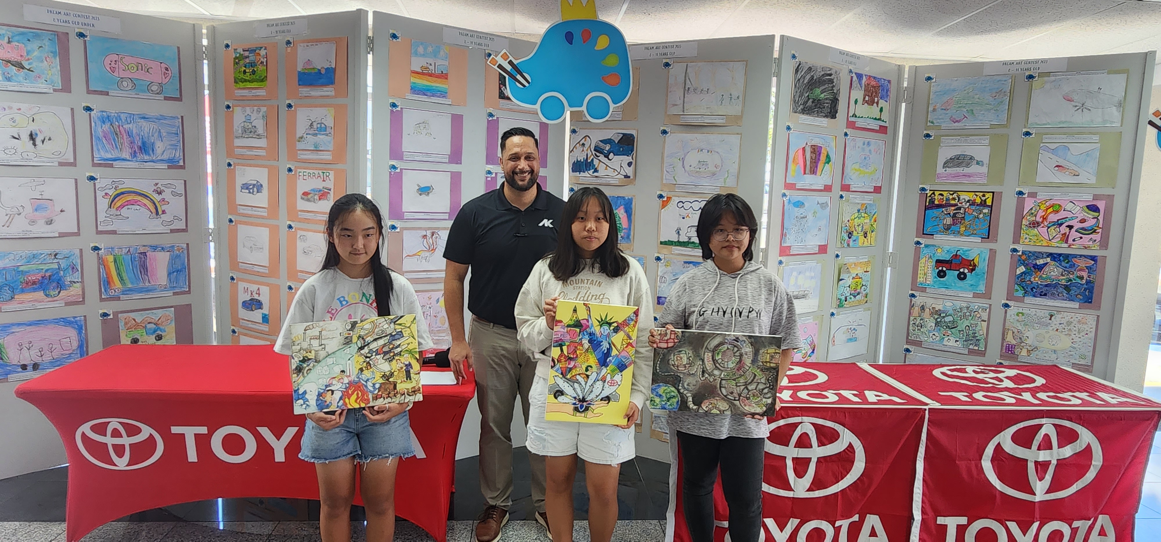 From left, the Category 12-15 winners of the 2023 Toyota Dream Car Art Contest: Eunho Park, 1st prize; Alyssa Kim, 2nd prize; and Yu Rong Jiang, 3rd prize. Behind them is Atkins Kroll Sales Manager Kevin Barnes.