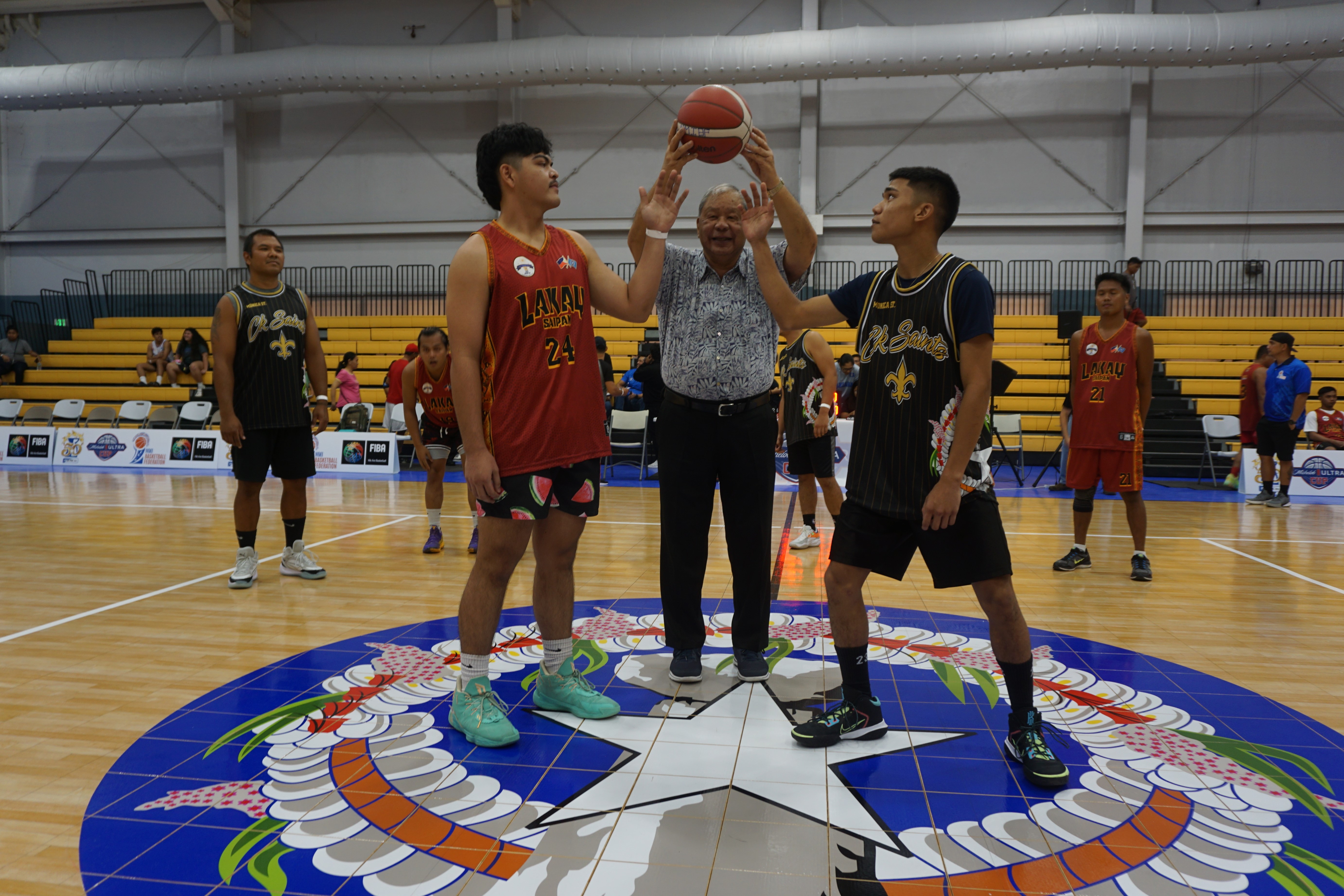 Lt. Gov. David M. Apatang poses for the ceremonial tip off of the opening game with players from Save More and CK Saints.