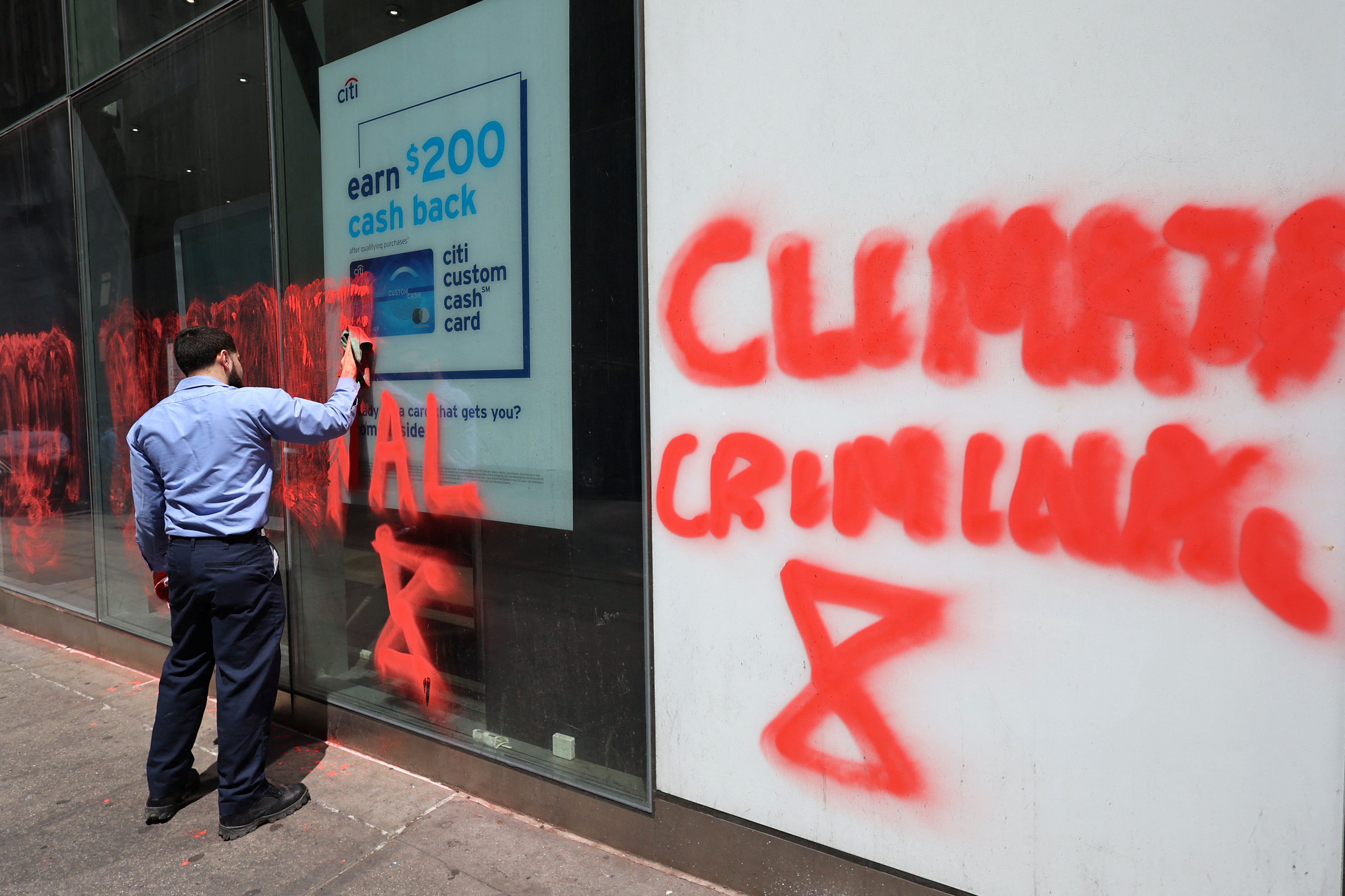 A worker cleans off a spray-painted message left by climate protestors on the outside of a Citibank branch in Midtown Manhattan in New York City, New York, U.S., April 24, 2023. REUTERS/Mike Segar