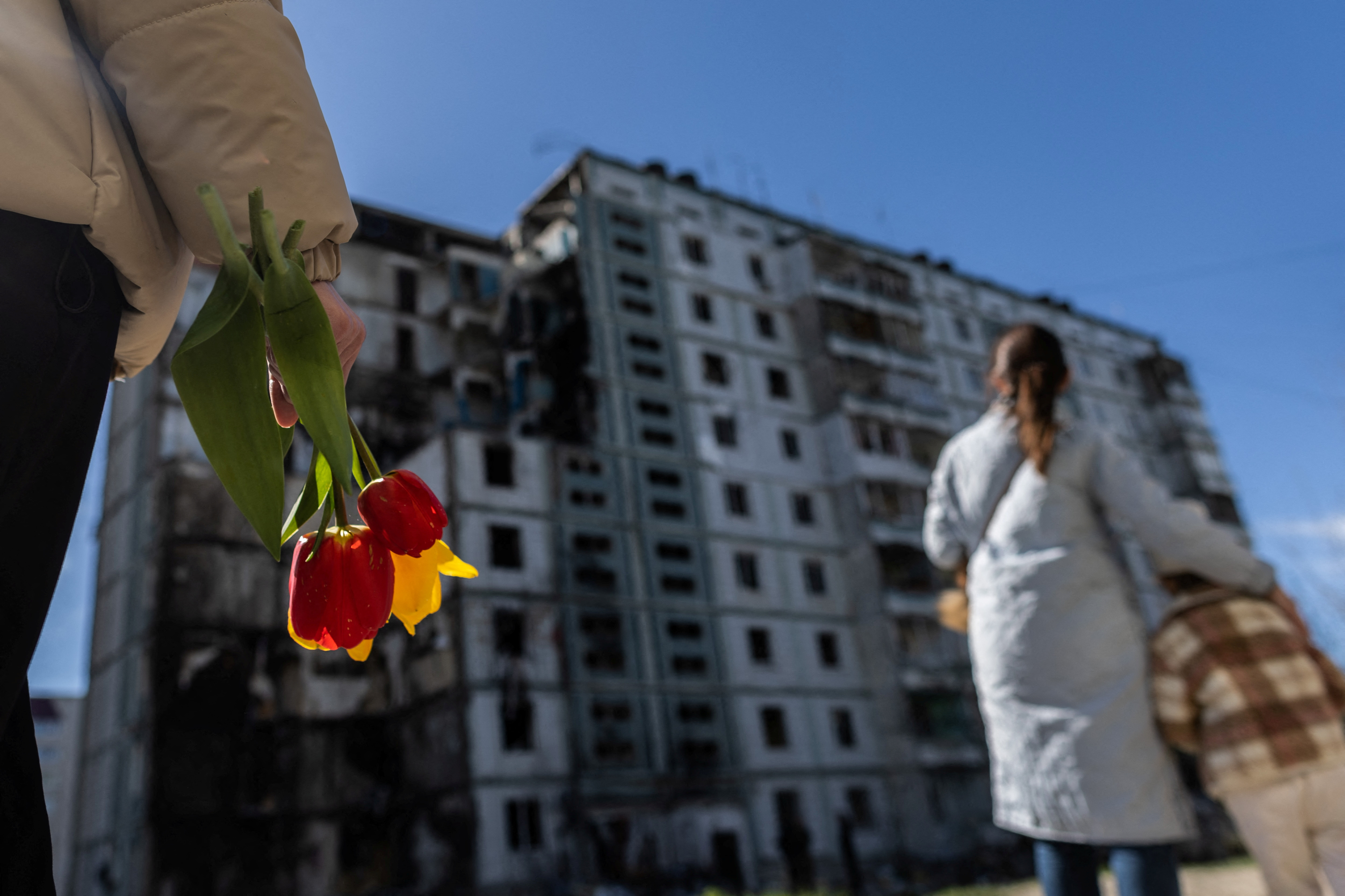 A woman carries flowers as she pays tribute to civilian people killed yesterday by a Russian missile strike, amid Russia's attack on Ukraine, at a strike site in the town of Uman, Cherkasy region, Ukraine April 29, 2023. REUTERS/Carlos Barria
