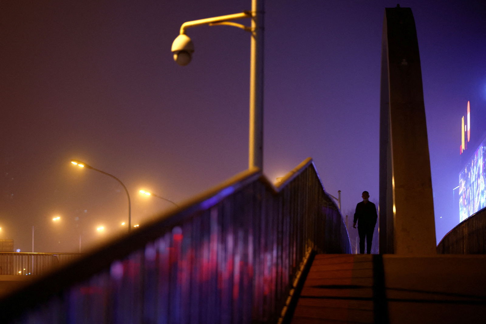FILE PHOTO: A man walks on an overpass amid a sandstorm as the city is shrouded in smog, in Beijing, China April 10, 2023. REUTERS/Tingshu Wang/File Photo