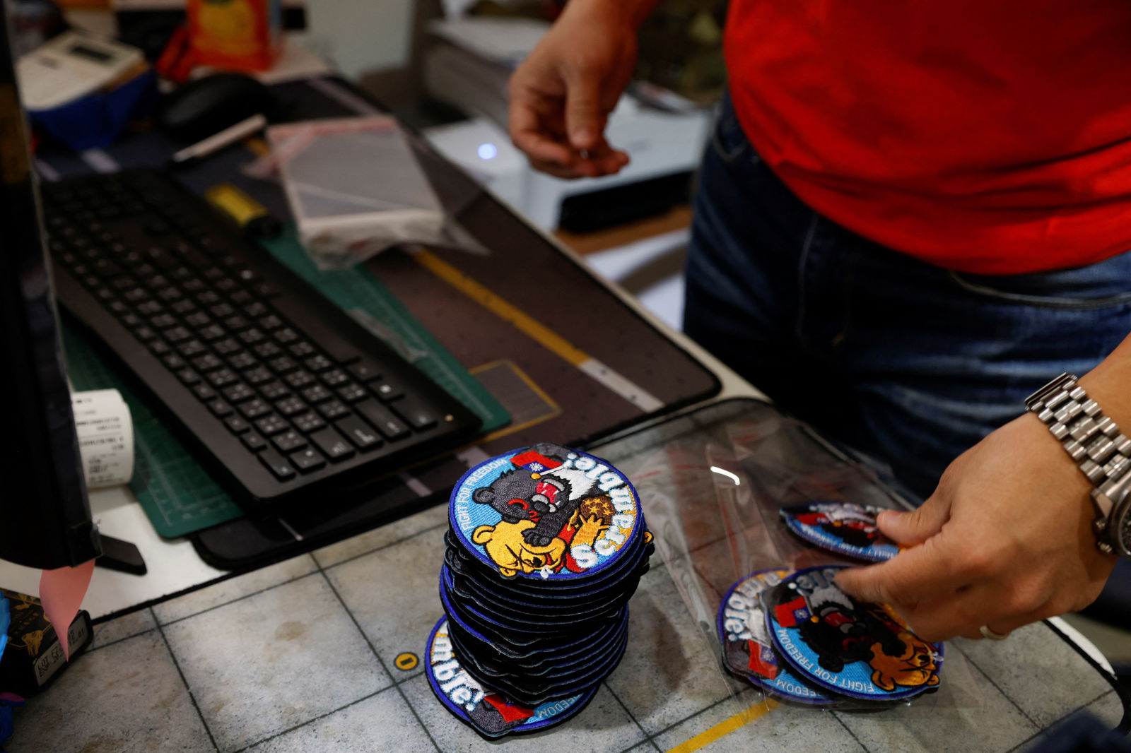 Alec Hsu puts patches depicting a Formosan black bear holding Taiwan’s flag and punching Winnie the Pooh, inside individual plastic bags at his store in Taoyuan, Taiwan, April 10, 2023. 