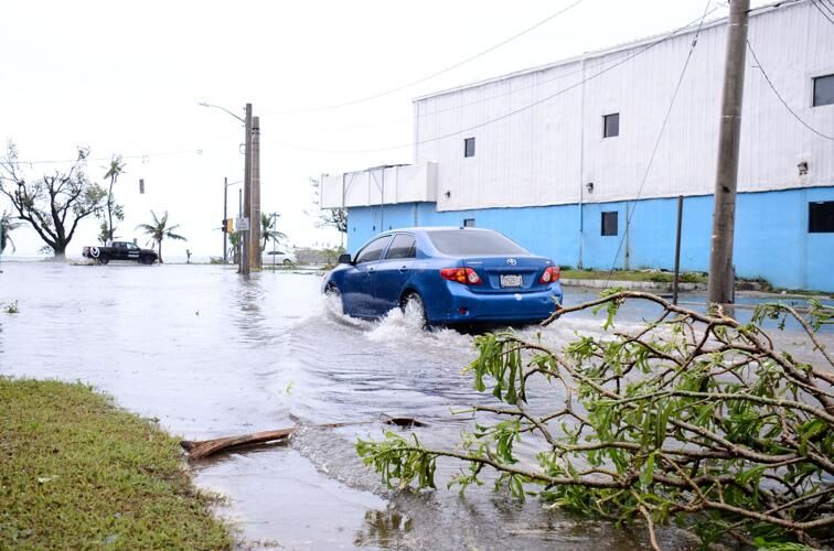 A car goes through a flooded portion of Hagåtña Thursday as debris litters the area. 