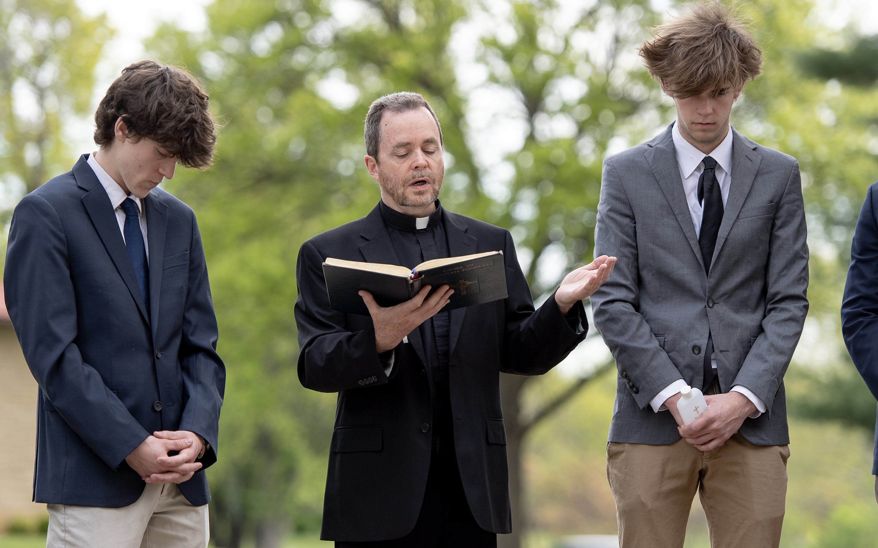 The Rev. Gary Menard reads from the Order of Christian Funerals during a funeral service for unclaimed deceased persons at the Mount Olivet Catholic Cemetery on Thursday, May 4, 2023, in Raytown, Missouri. Eight high schoolers from Rockhurst High School helped give the deceased a proper burial service. (Nick Wagner/The Kansas City Star/TNS)