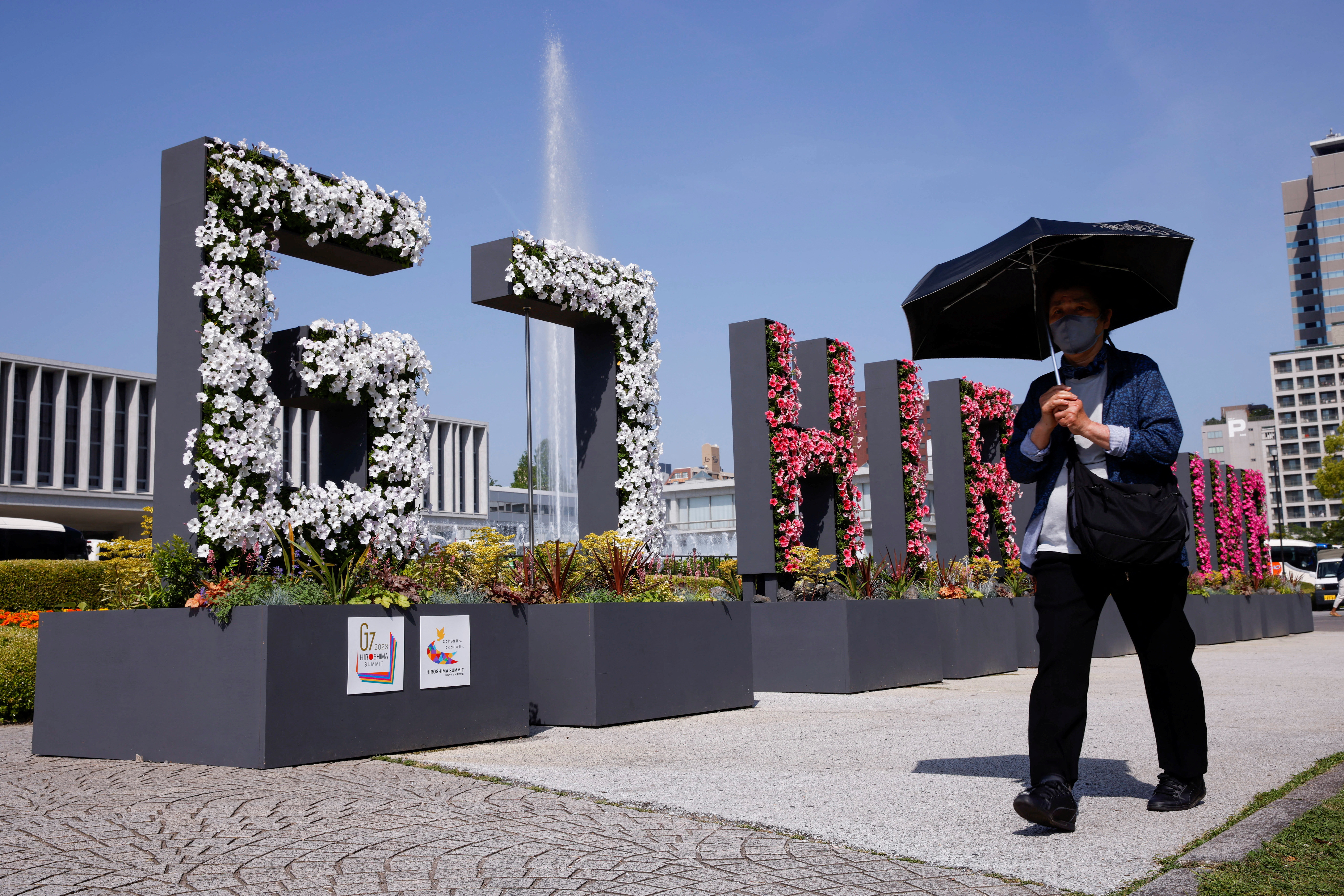 FILE PHOTO: A woman walks past a “G7 Hiroshima” flower installation near the Peace Memorial Museum, ahead of the G7 summit, in Hiroshima, Japan, May 17, 2023. REUTERS/Androniki Christodoulou