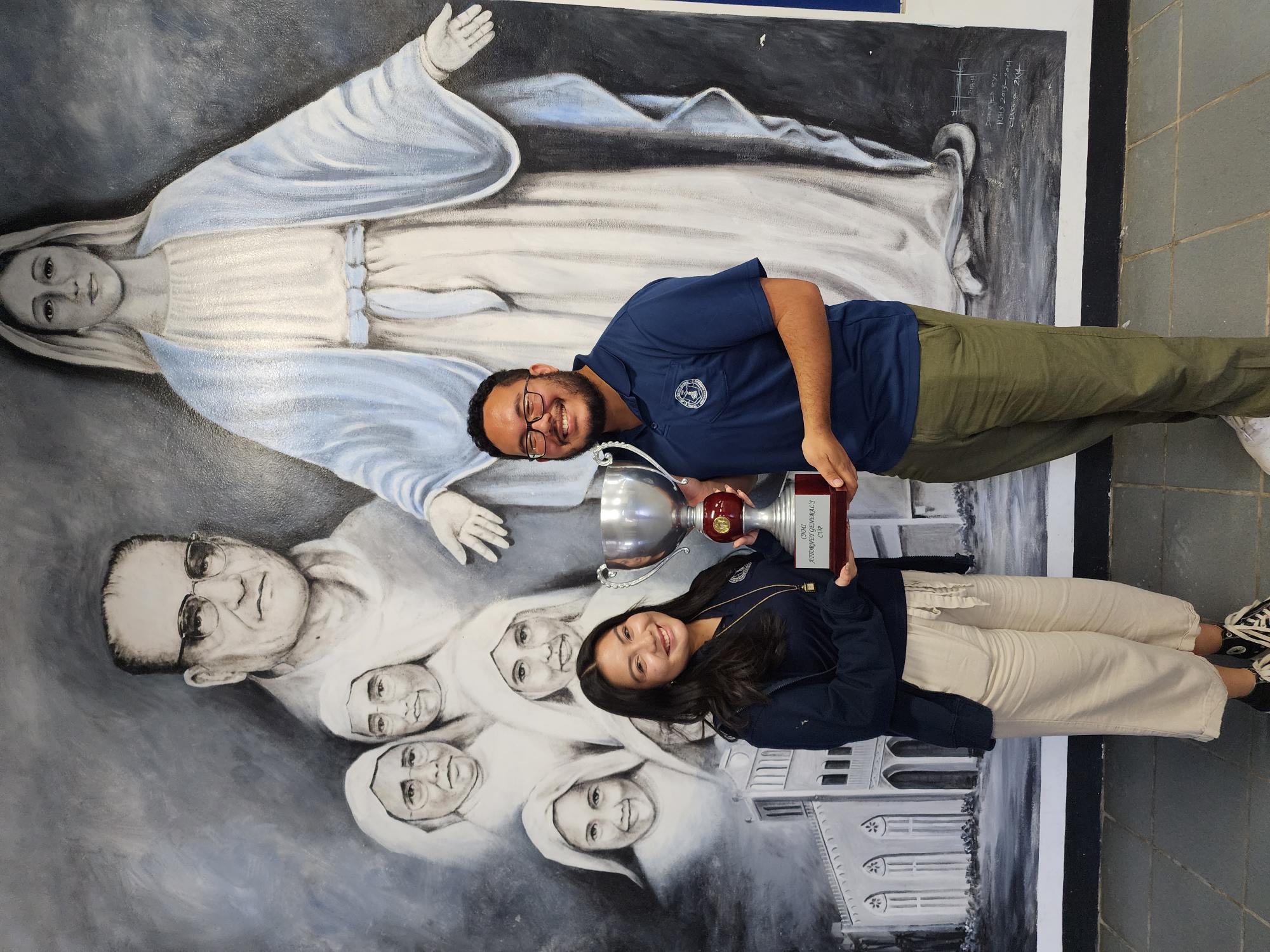 Jill Anne Mallari of Mount Carmel School and one of her coaches, Zeno Deleon Guerrero, MCS English teacher, pose with the perpetual AG’s Cup which Mallari won on Friday.