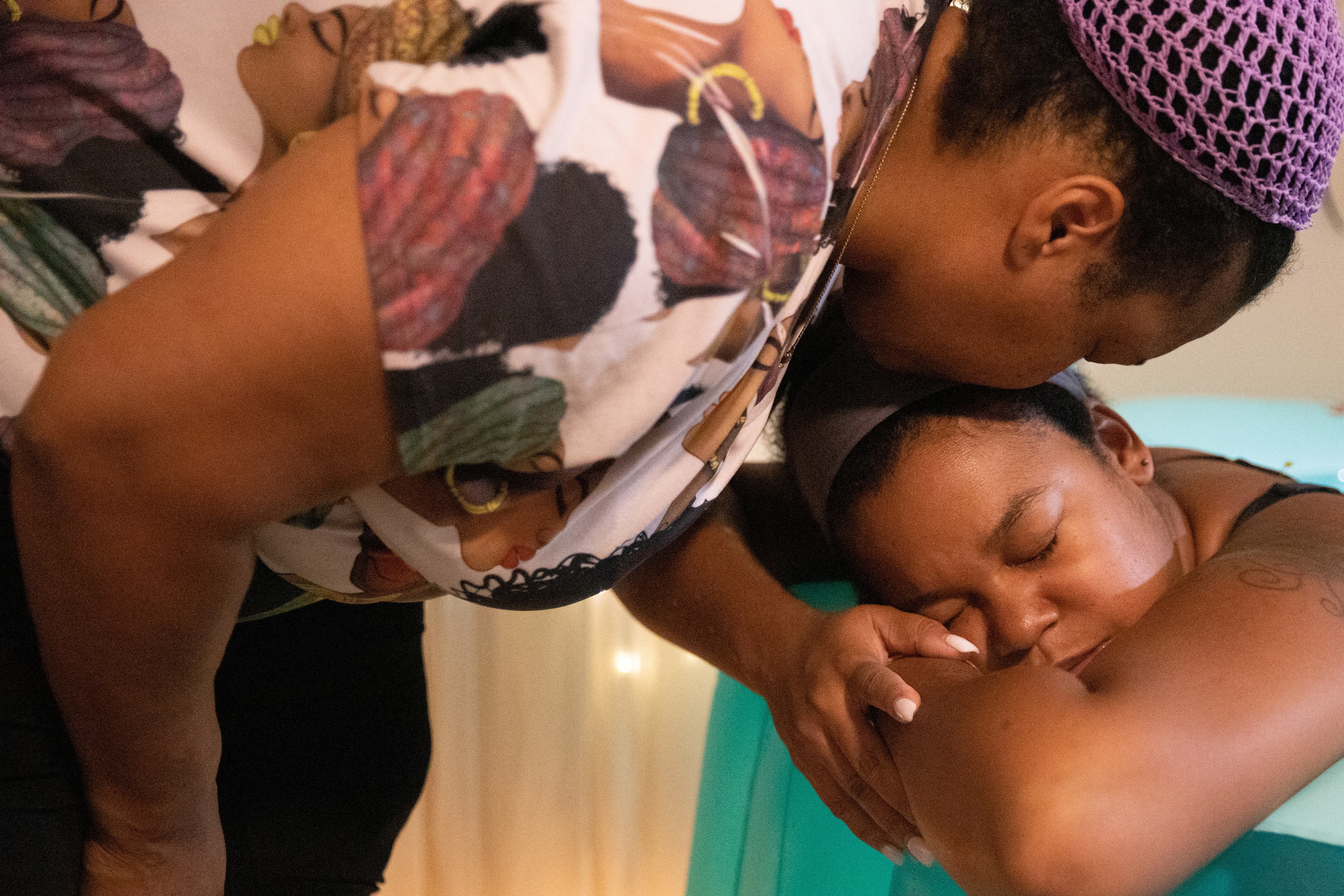 Holistic doula Ciara Clark, 34, receives a kiss from her mother Elle T Parker, 53, while she labors in her birthing pool at her home birth in Toms River, New Jersey, U.S., September 11, 2022. REUTERS/Joy Malone