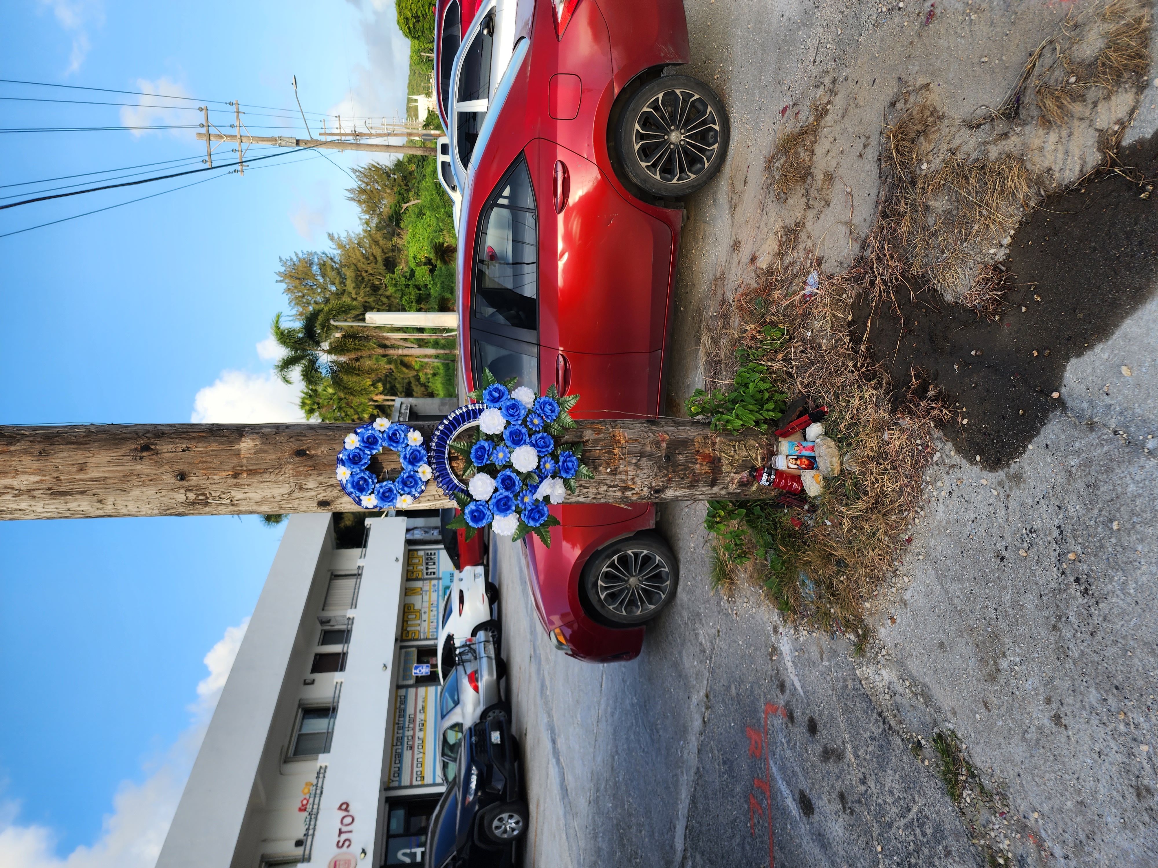 Flowers and candles are seen in the Kannat Tabla area where a car crashed early Saturday morning, killing the driver and injuring the passenger.