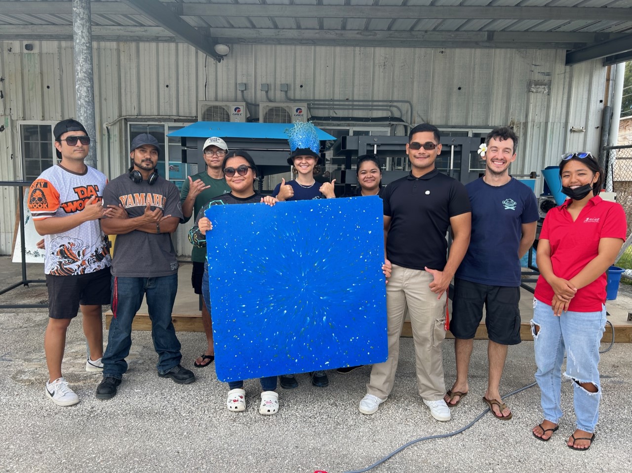 NMTECH staff, MINA Rangers, and Sea Monkey Project staff pose with a 1mx1m plastic sheet made on Saipan.