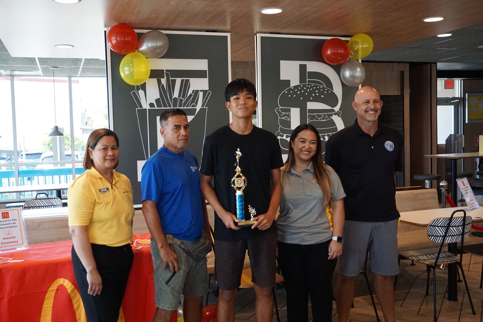 Marianas High School’s Cody Shimizu, center, the U18 boys MVP, with McDonald's Middle Road general manager Jocelyn Asistores, Northern Marianas Athletics development officer Elias Rangamar, McDonald's of Guam and Saipan Executive Assistant to the President Mable Ayuyu Glenn, and PSS Athletics Program Director Nick Gross, during the awards ceremony at McDonald's Middle Road on Monday.