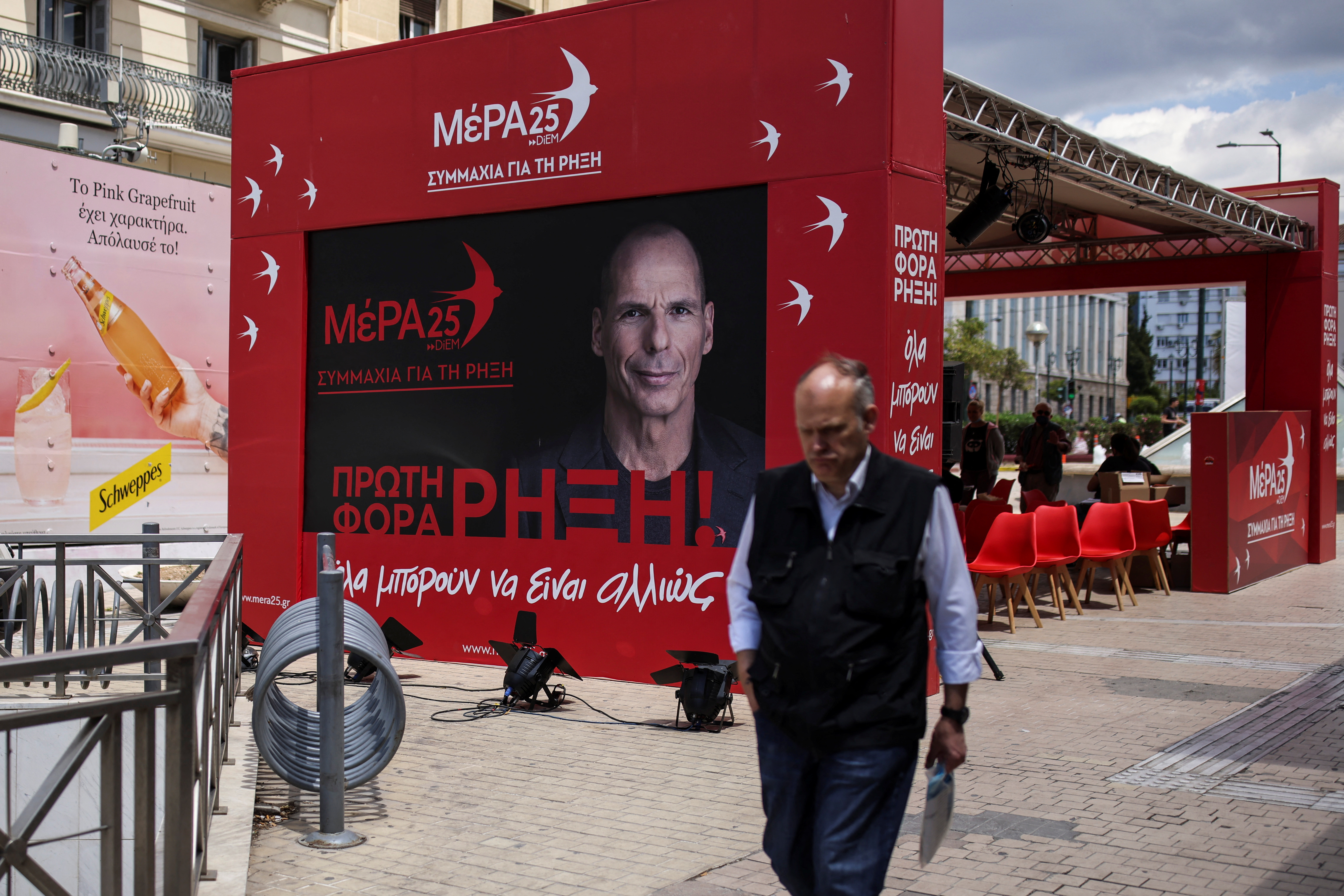 A man walks past the pre-election kiosk of the MeRA25 party, depicting the party's leader Yanis Varoufakis, in Athens, Greece, May 18, 2023. REUTERS/Stelios Misinas