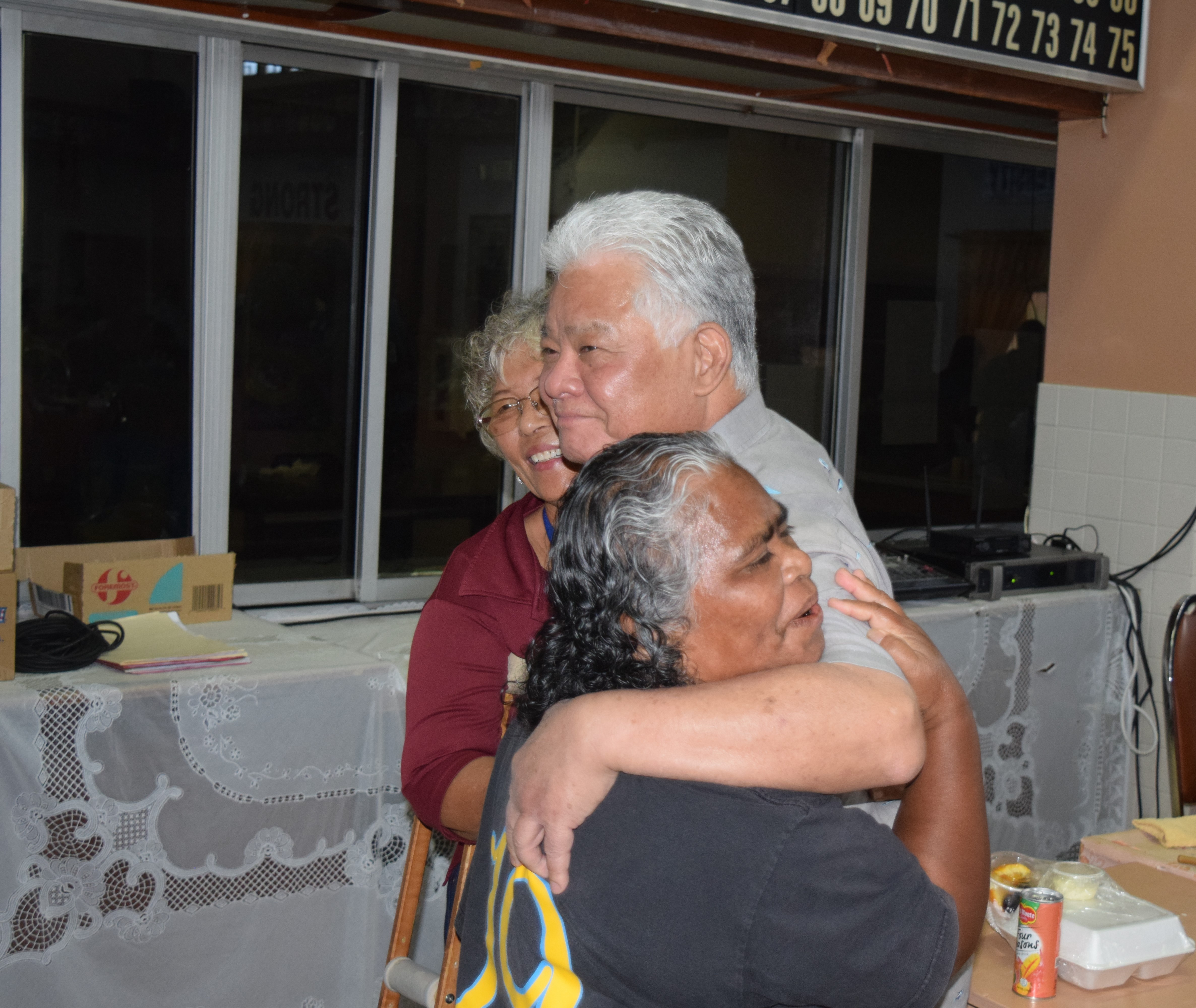 Gov. Arnold I. Palacios is hugged by two senior citizens at the Office on Aging on Thursday.