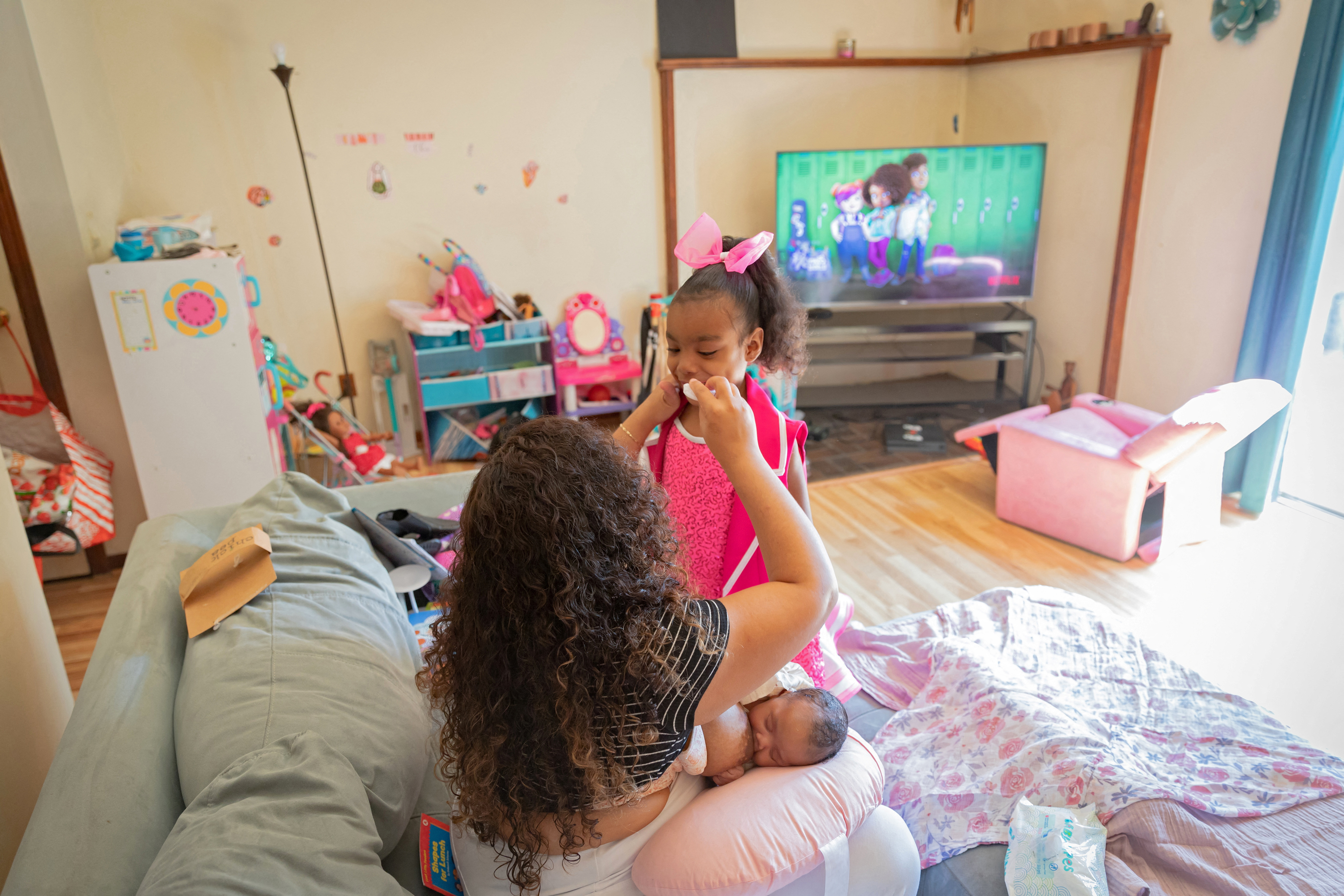 Bianca Haynes wipes her six-year-old daughter Afena's mouth while breastfeeding her newborn daughter Zuri in Elmwood Park, New Jersey, U.S., May 30, 2022. REUTERS/Joy Malone