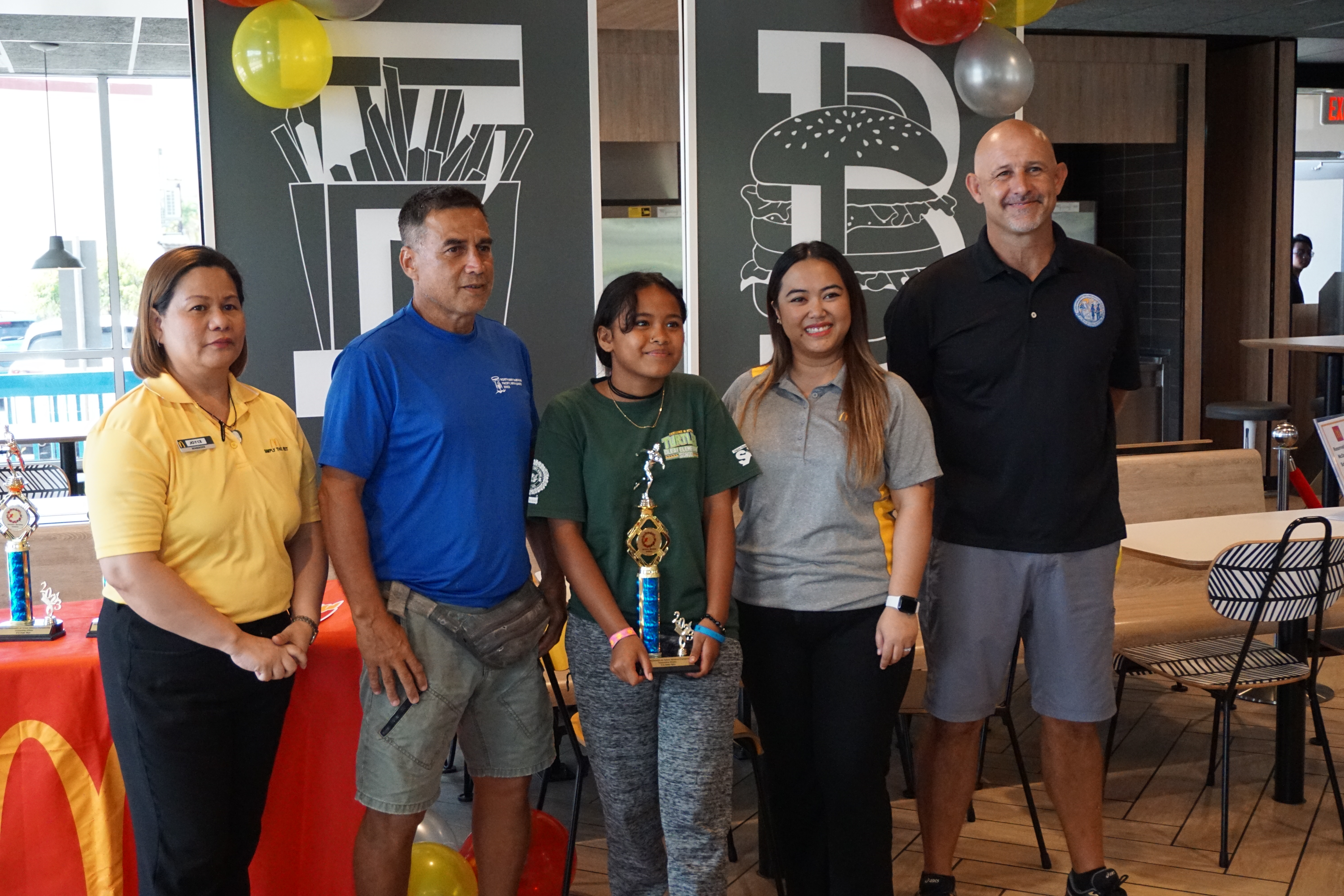 Oleai Elementary School’s Gabriella Ruben, center, the U12 girls MVP, with McDonald's Middle Road general manager Jocelyn Asistores, Northern Marianas Athletics development officer Elias Rangamar, McDonald's of Guam and Saipan Executive Assistant to the President Mable Ayuyu Glenn, and PSS Athletics Program Director Nick Gross, during the awards ceremony at McDonald's Middle Road on Monday.  