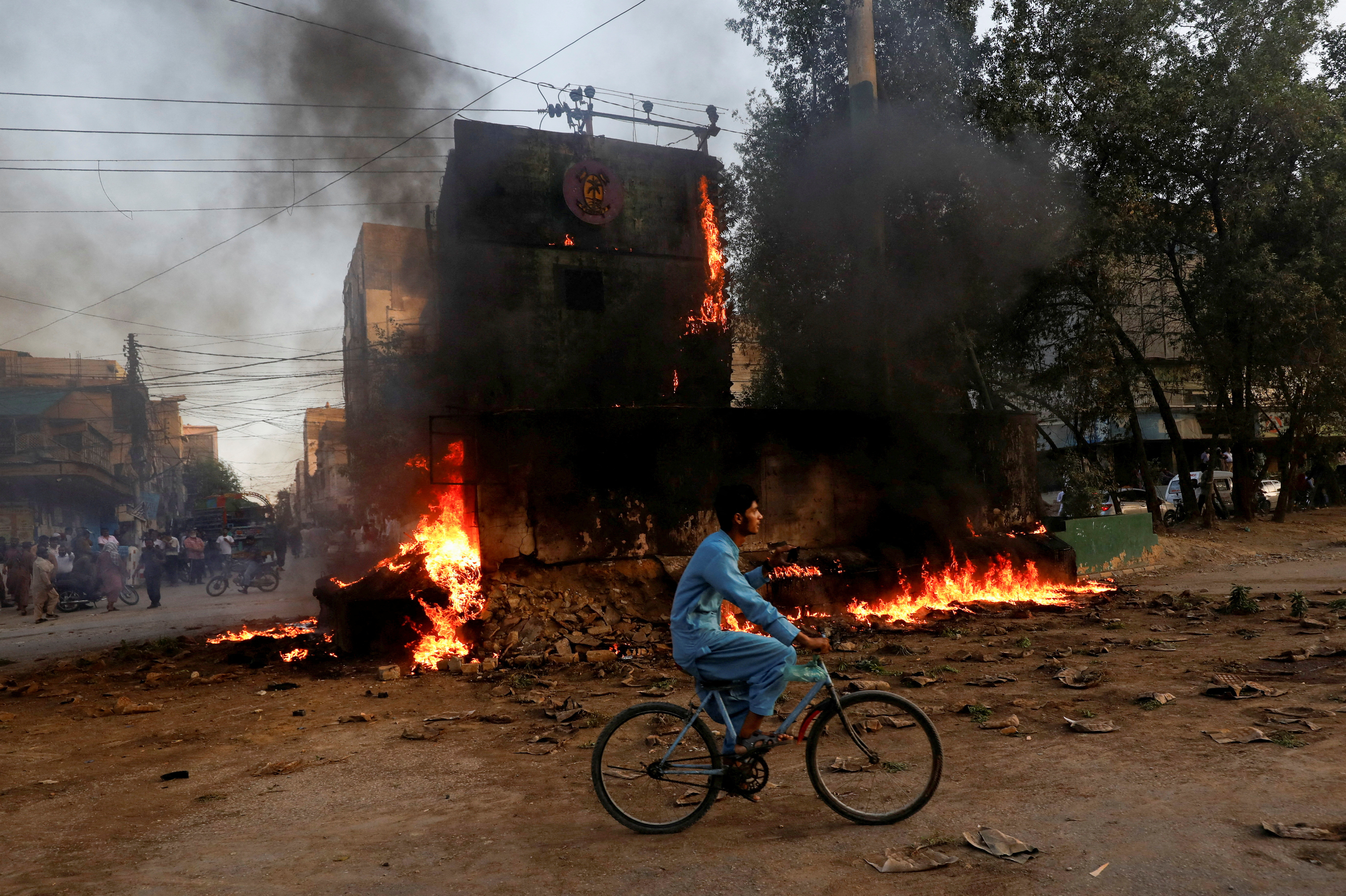A boy rides past a paramilitary check post, that was set afire by the supporters of Pakistan's former Prime Minister Imran Khan, during a protest against his arrest, in Karachi, Pakistan May 9, 2023. REUTERS/Akhtar Soomro