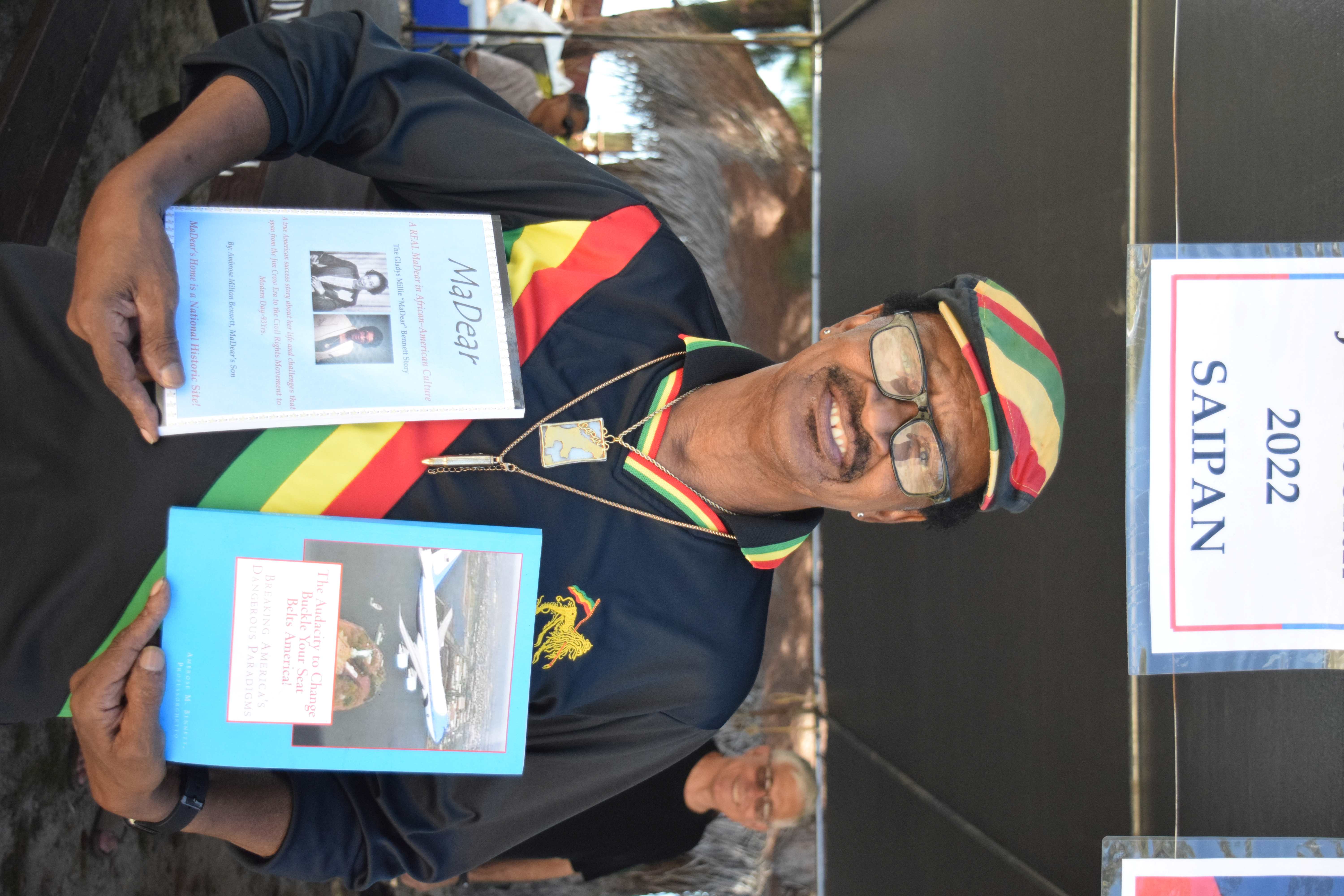 Ambrose Bennett holds two books he authored during the Juneteenth celebration he hosted at the Civic Center beach in Susupe in 2022.