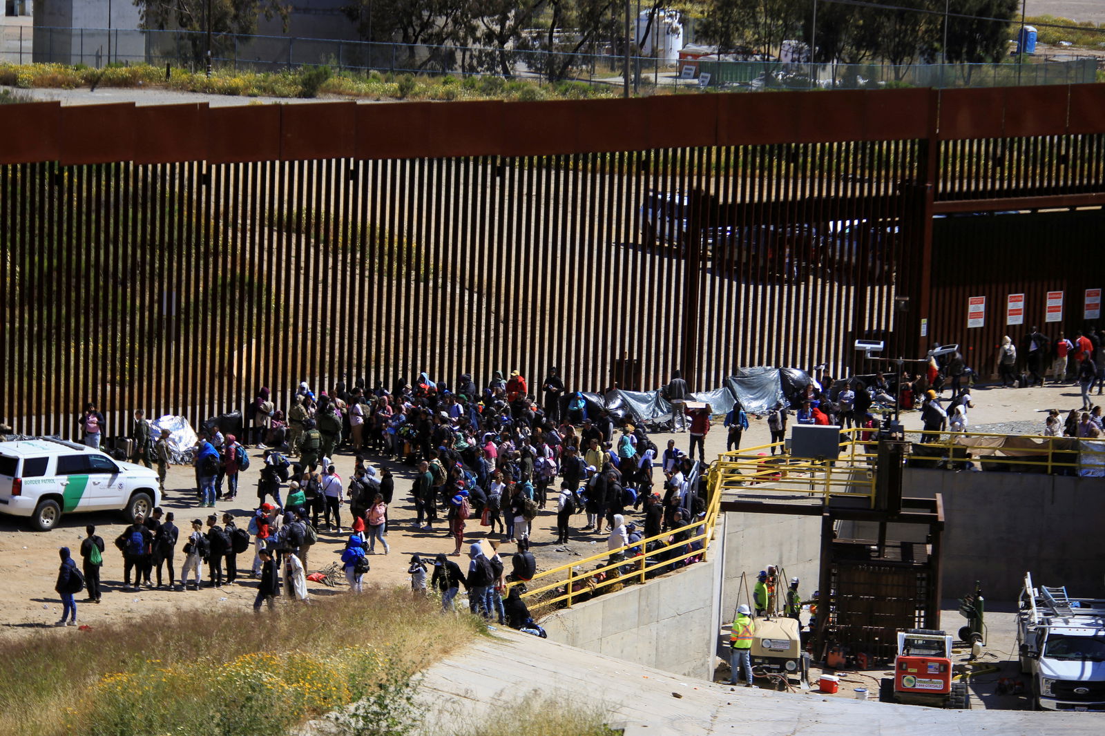FILE PHOTO: Migrants gather between the primary and secondary border fences in San Diego as the United States prepares to lift COVID-19 era restrictions known as Title 42, that have blocked migrants at the U.S.- Mexico border from seeking asylum since 2020, as seen from Tijuana, Mexico May 8, 2023. REUTERS/Aimee Melo/File Photo