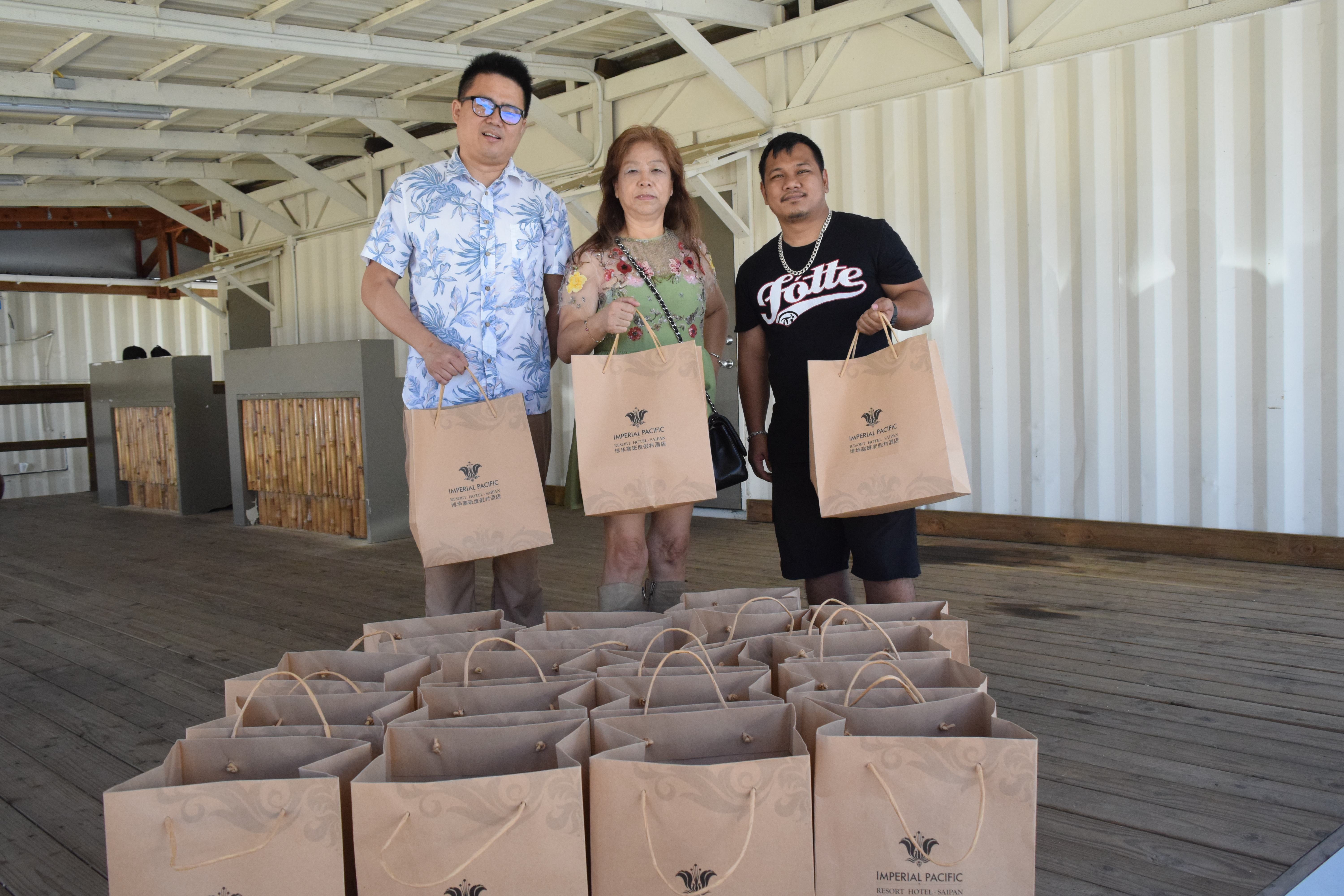 Imperial Pacific International major shareholder Cui Li Jie, center, human resource business partner How Yo Chi and Mel Manglona, a staff member of Sen. Paul Manglona's office, hold bags of groceries at the Saipan commuter terminal on Saturday.
