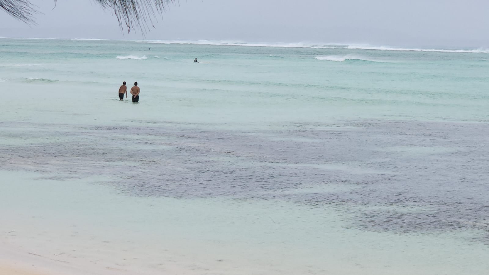 Three individuals are seen in the waters off Bantalan beach on Wednesday while Typhoon Mawar approached the Marianas.