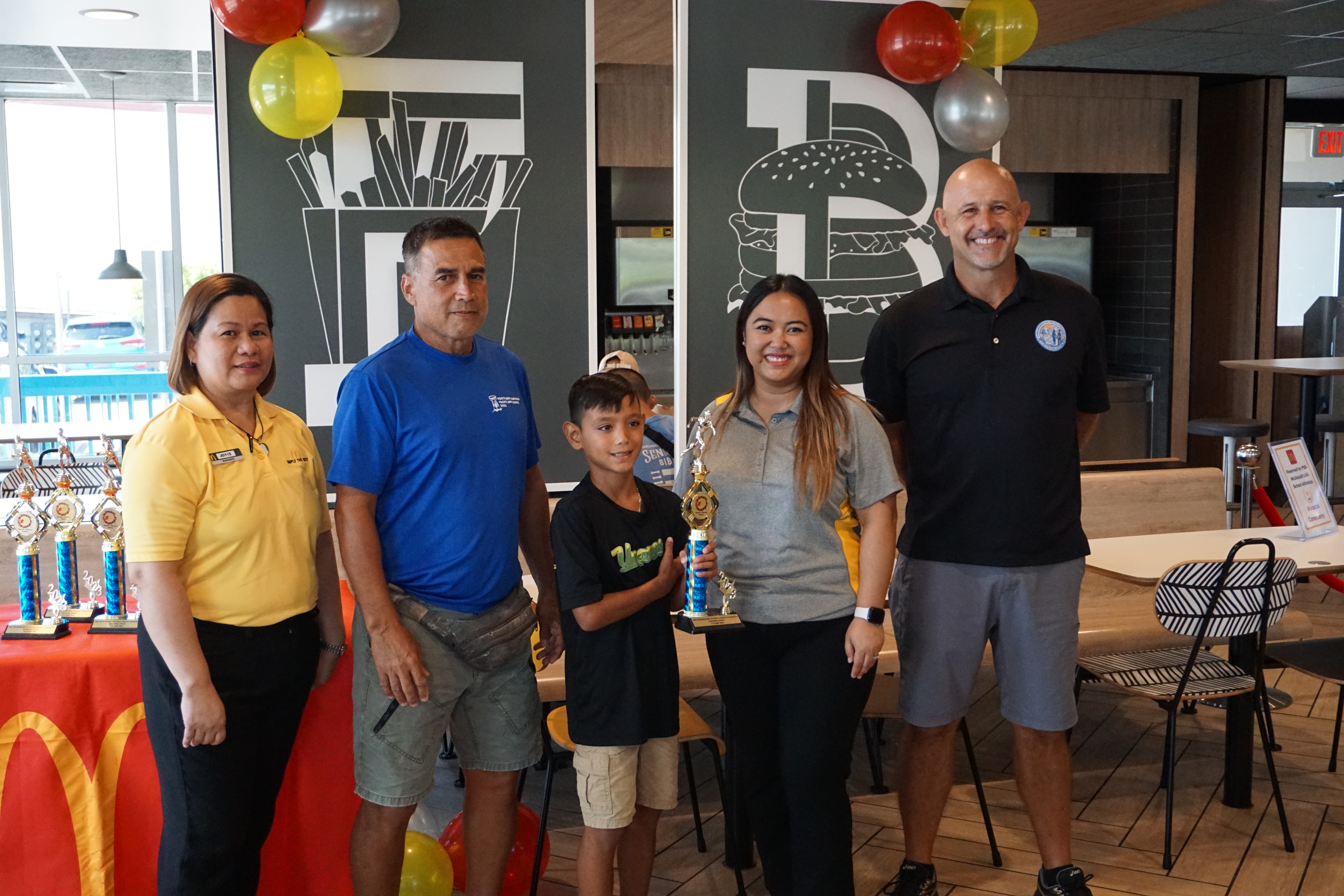 Koblerville Elementary School’s Dean Aldan, center, the U9 boys MVP, with McDonald's Middle Road general manager Jocelyn Asistores, Northern Marianas Athletics development officer Elias Rangamar, McDonald's of Guam and Saipan Executive Assistant to the President Mable Ayuyu Glenn, and PSS Athletics Program Director Nick Gross, during the awards ceremony at McDonald's Middle Road on Monday.  