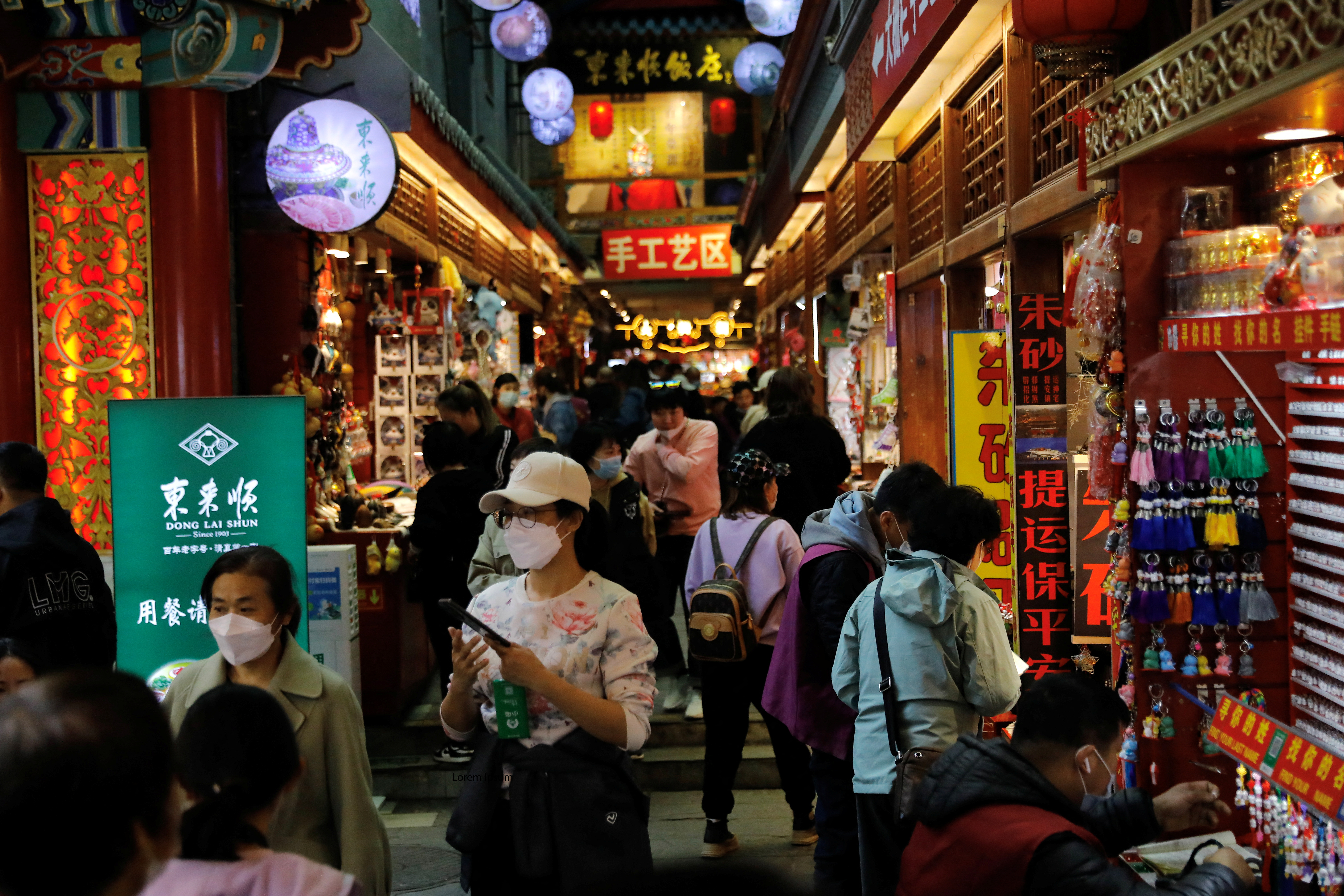 FILE PHOTO: People visit a market at the tourism site of Qianmen street, in Beijing, China March 14, 2023. REUTERS/Tingshu Wang