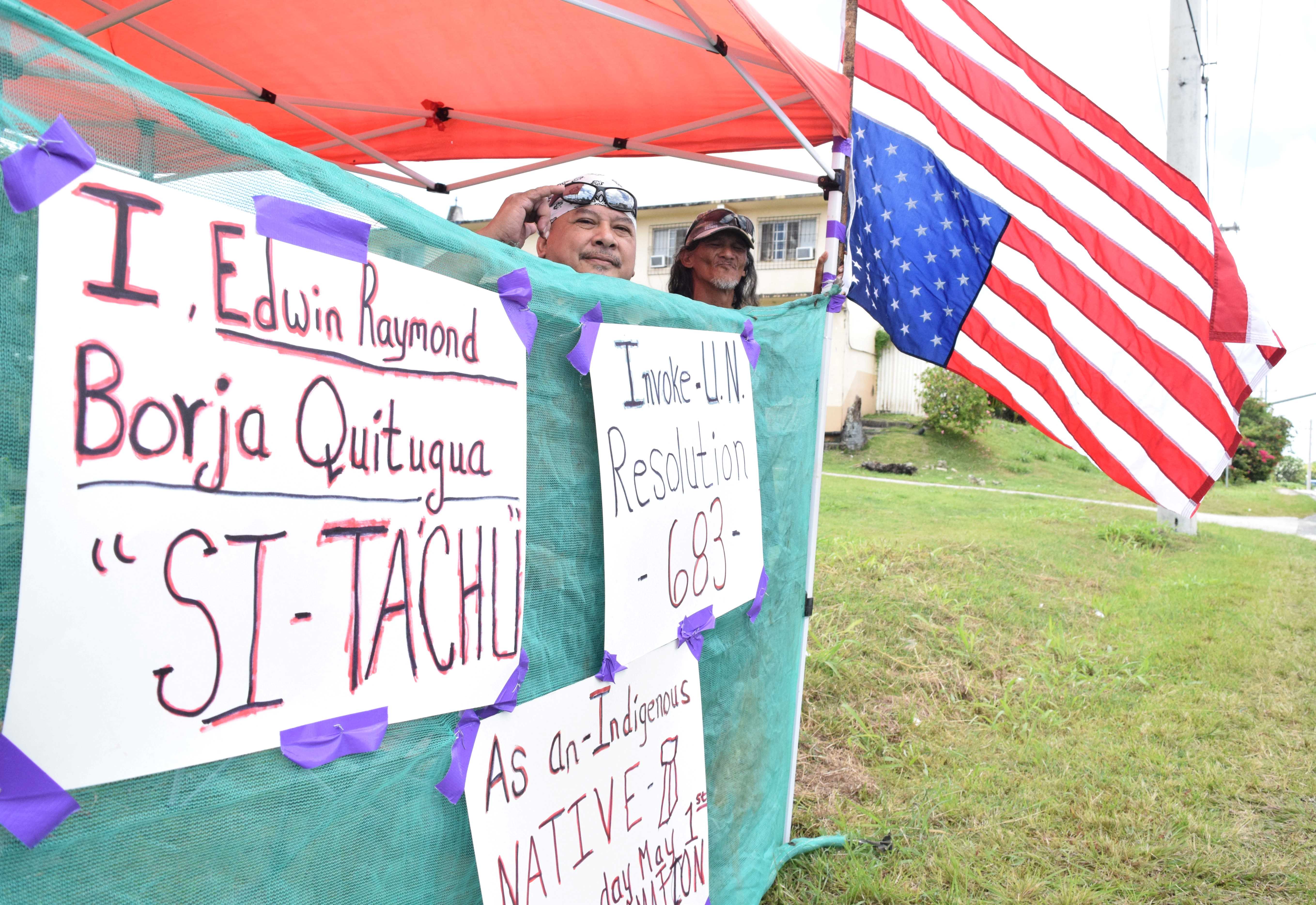Indigenous rights activists Raymond Quitugua and Herman Tudela stand next to an inverted U.S. flag during their protest action across from the United States Courthouse on Middle Road.
