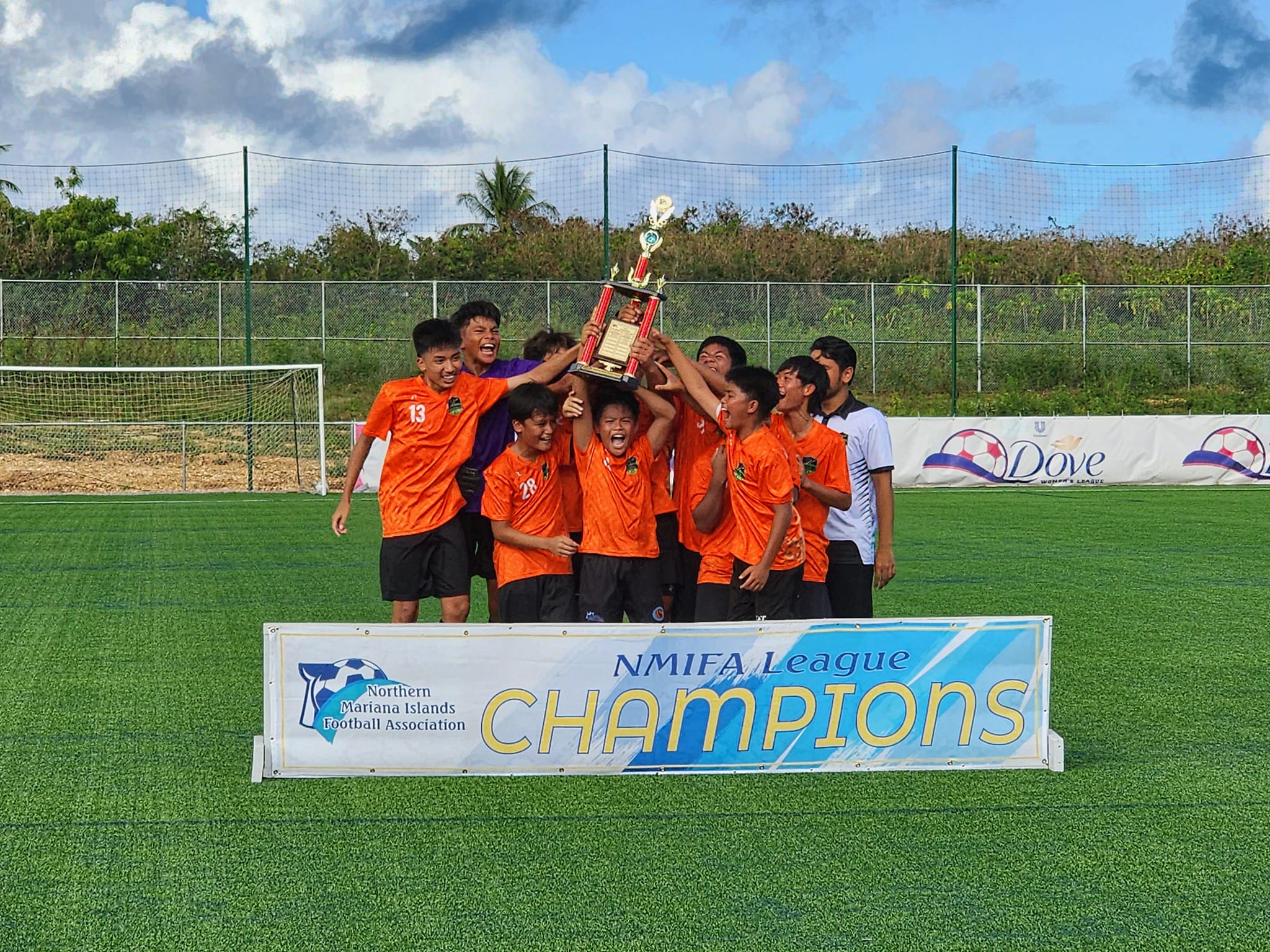 The Kanoa Football Club players celebrate raise the U14 boys division championship trophy after defeating the Matansa Football Club in the title match of the TakeCare Youth Soccer League at the NMI Soccer Training Center in Koblerville on Saturday.