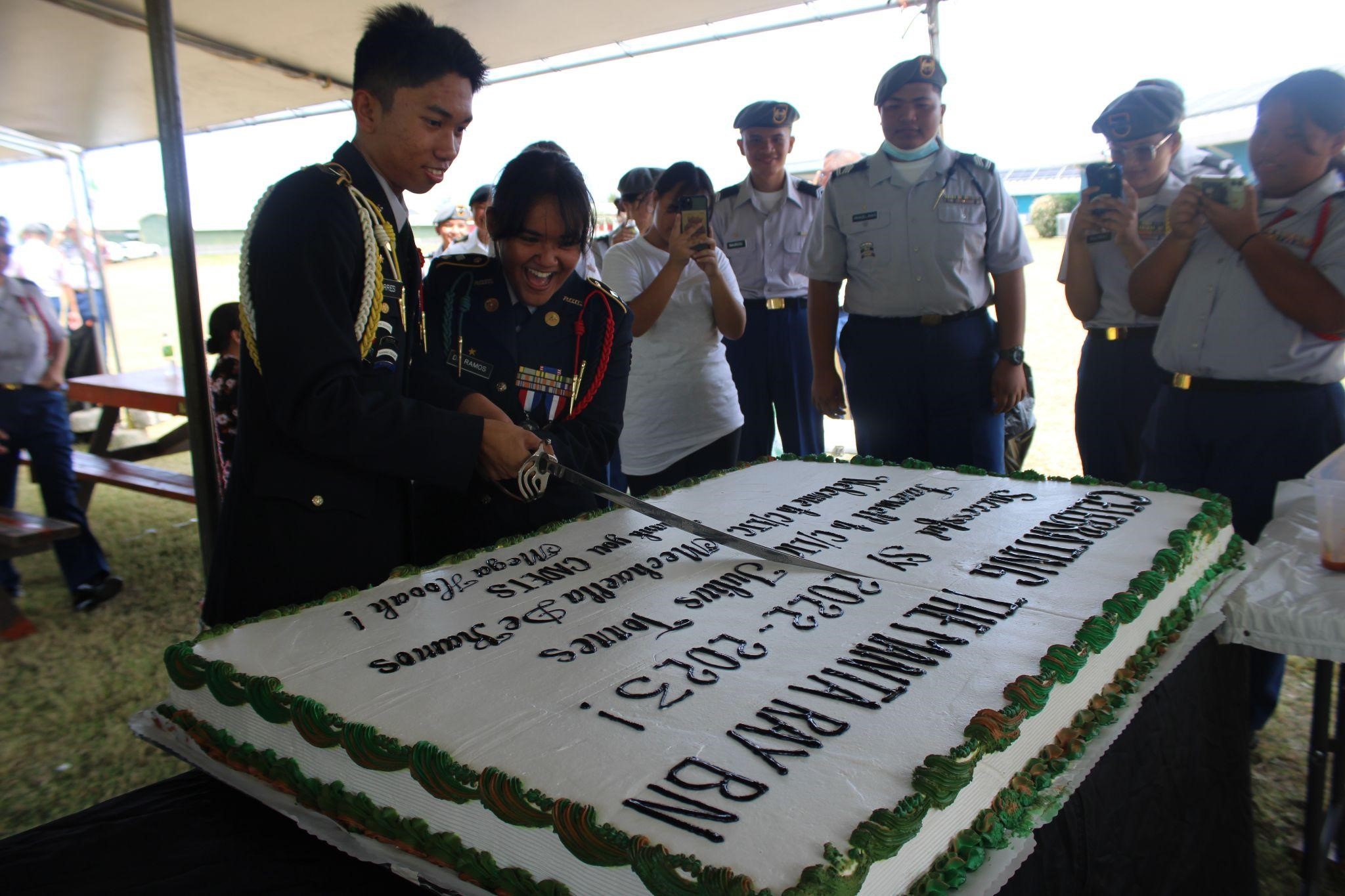 The outgoing and incoming commanders cut the cake with a saber.