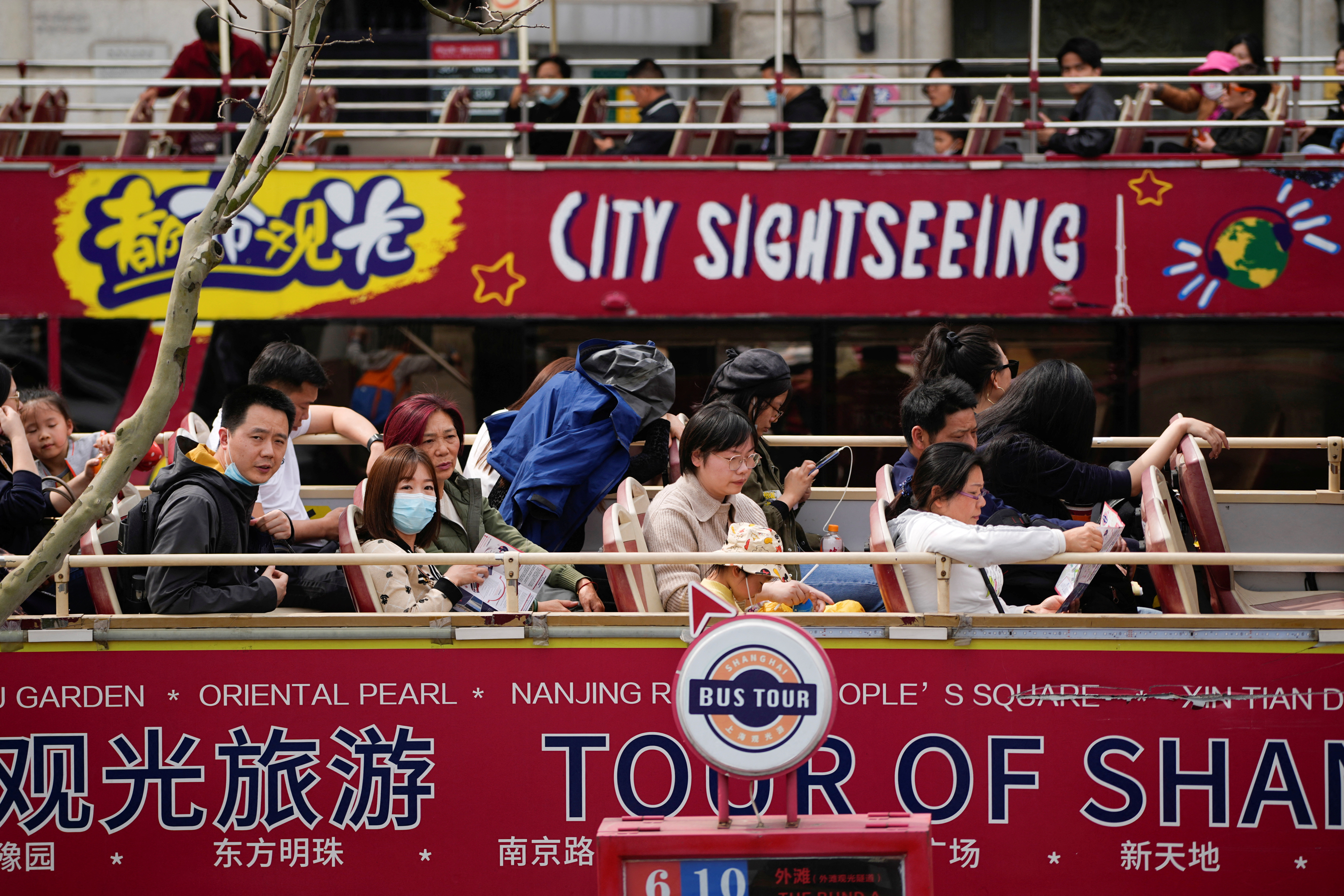 FILE PHOTO: Tourists ride on a tourist double-decker bus in Shanghai, China, March 15, 2023. REUTERS/Aly Song
