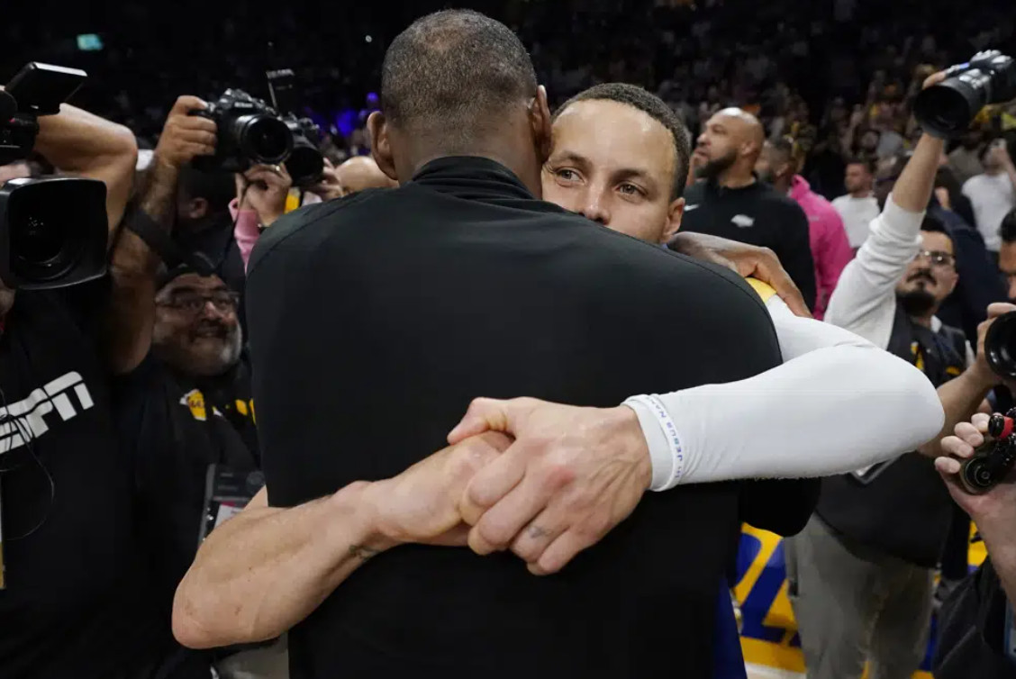 Los Angeles Lakers forward LeBron James, back to camera, hugs Golden State guard Stephen Curry after Game 6 of an NBA basketball Western Conference semifinal series Friday, May 12, 2023, in Los Angeles. Los Angeles won 122-101 to take the series and advance to the conference championship.