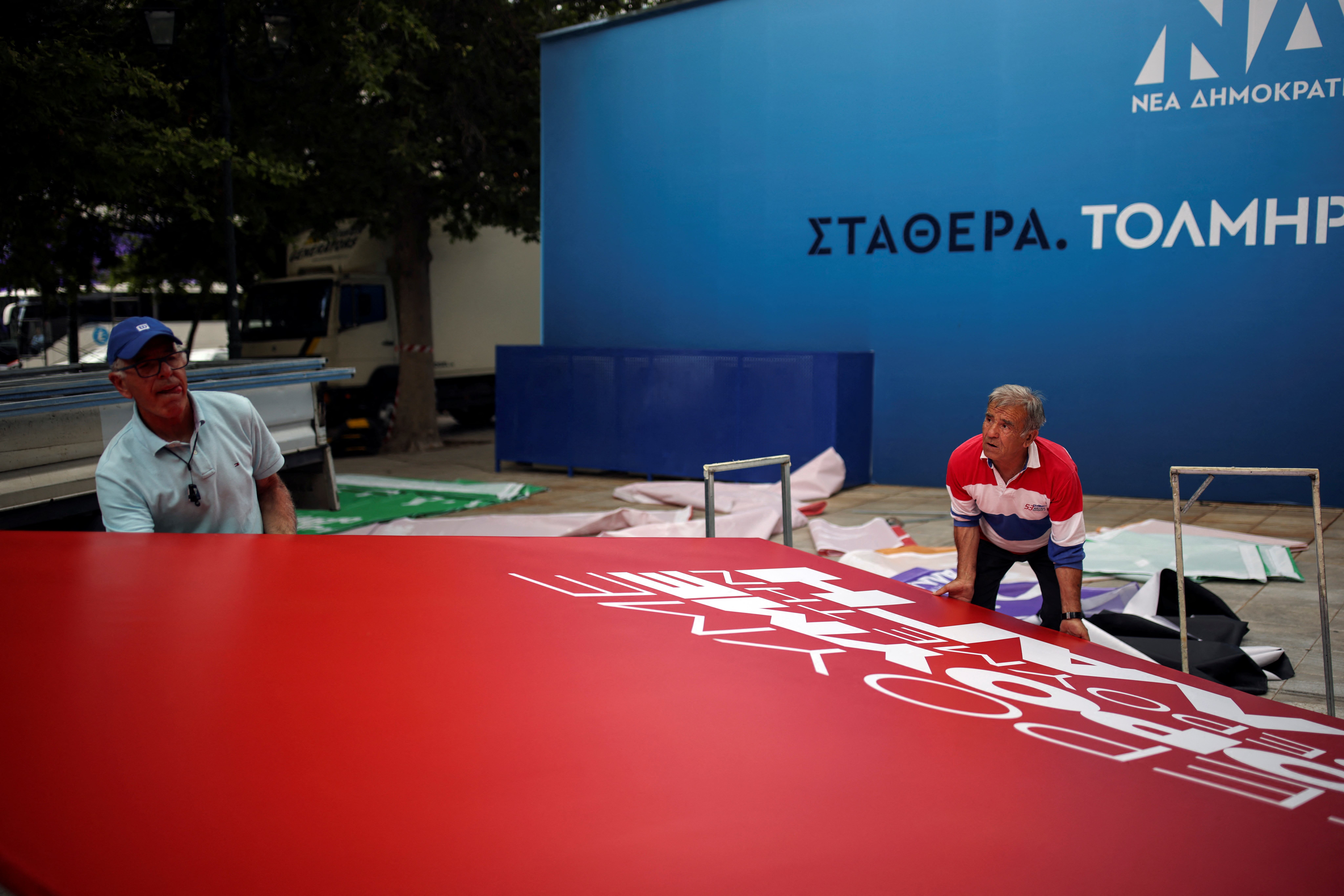 Workers hold a banner during preparations for the pre-election speech of leftist Syriza party leader Alexis Tsipras, in Athens, Greece, May 18, 2023. REUTERS/Stelios Misinas