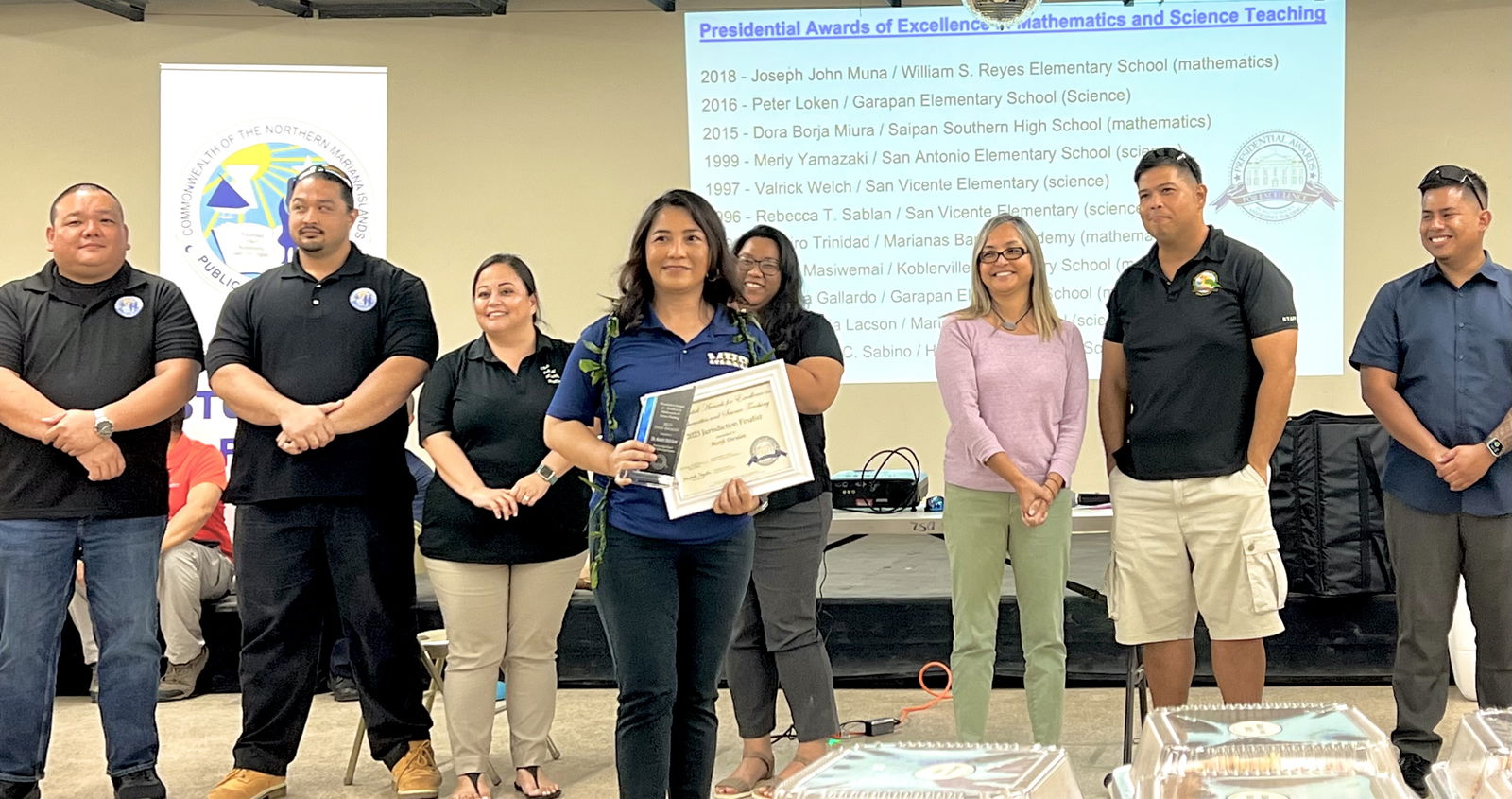 Dr. Marifi Doculan holds her glass trophy and plaque as one of the finalists in the 2023 Presidential Awards for Excellence in Mathematics and Science Teaching or PAEMST. Also in photo are acting Commissioner of Education Eric Magofna, past PAEMST finalist and Board of Education Teacher Representative Dr. Dora B. Miura, 2023 finalist Dr. Patrick Castillon, 2023 Teacher of Year Donovan Tudela, PSS Human Resources Officer Lucretia Deleon Guerrero, Interim Instructional Technology and Distance Education Director Lorraine Catienza and acting Finance and Budget Officer Michael Babauta.