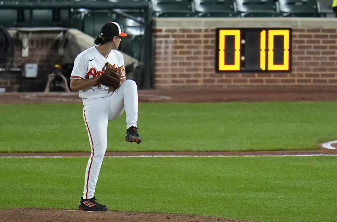 The pitch clock is visible as Baltimore Orioles starting pitcher Dean Kremer winds up to deliver during the sixth inning of a baseball game against the Boston Red Sox, April 24, 2023, in Baltimore, Md.