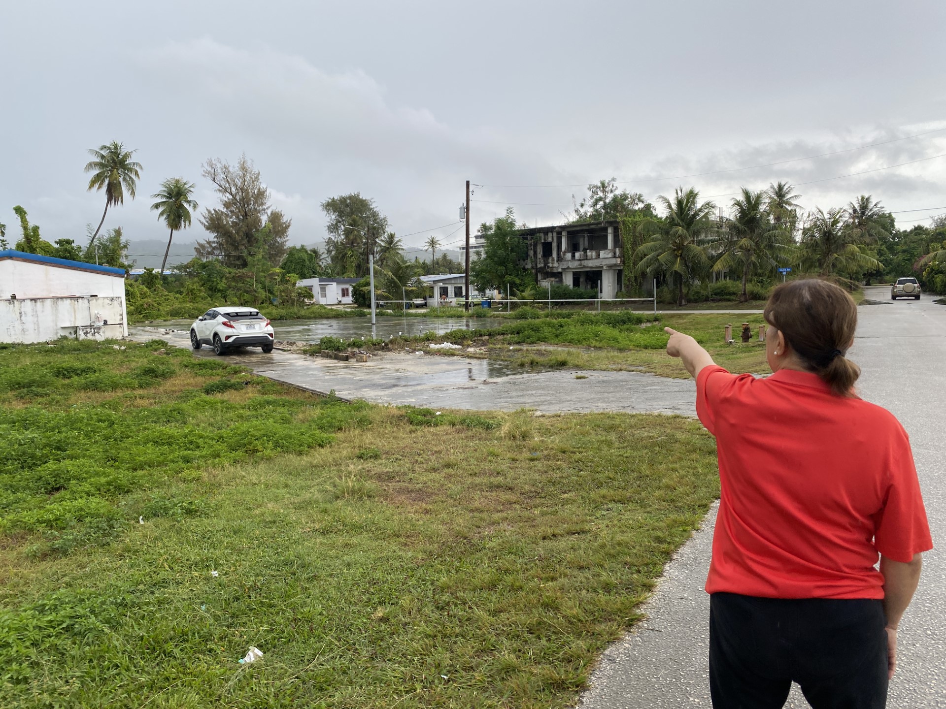 Laidy Ignacio points toward her home in Susupe on Tuesday. She’s worried that winds could knock debris from a tree onto her house.