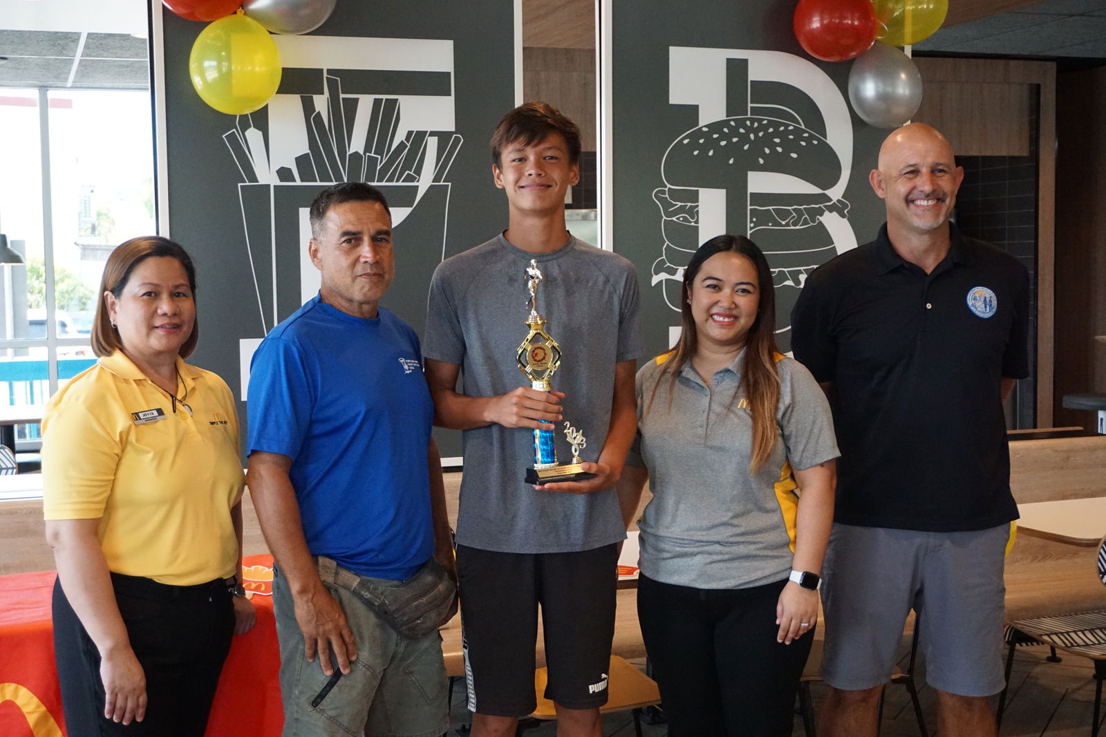 Saipan International School’s Moshe Sikkel, center, the U14 boys MVP, with McDonald's Middle Road general manager Jocelyn Asistores, Northern Marianas Athletics development officer Elias Rangamar, McDonald's of Guam and Saipan Executive Assistant to the President Mable Ayuyu Glenn, and PSS Athletics Program Director Nick Gross, during the awards ceremony at McDonald's Middle Road on Monday.