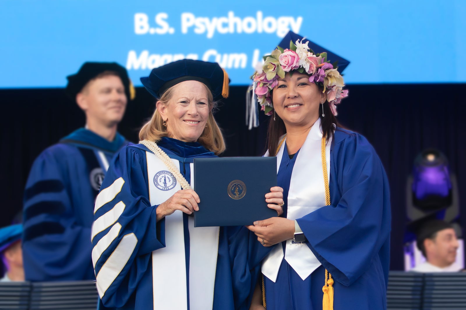 Linda Yoshimoto, right, Bank of Hawai‘i Kapolei branch manager, receives her diploma from Chaminade University. She is the 20th graduate through Bank of Hawai‘i’s College Assistance Program, which fully covers an employee’s tuition.