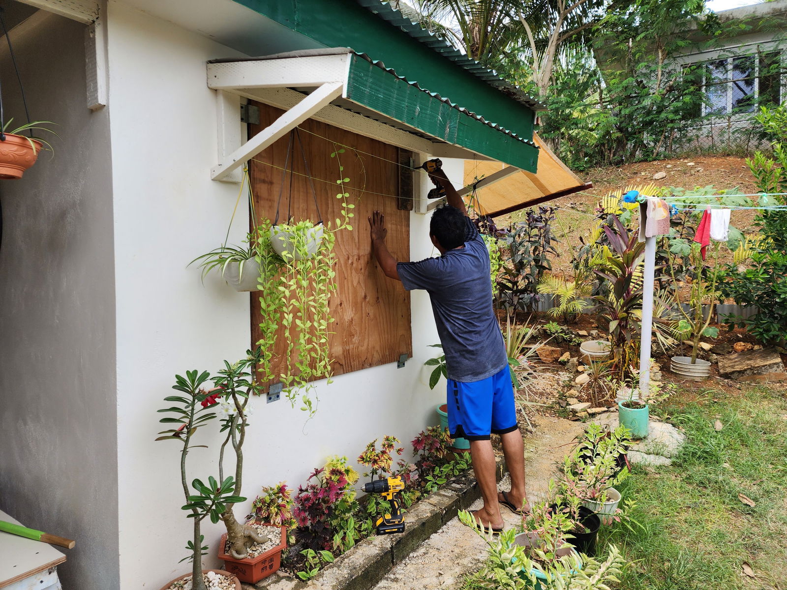Oreel Poblete boards the windows of his home in preparation for Tropical Storm Mawar at the Sugar King Estate on Monday.