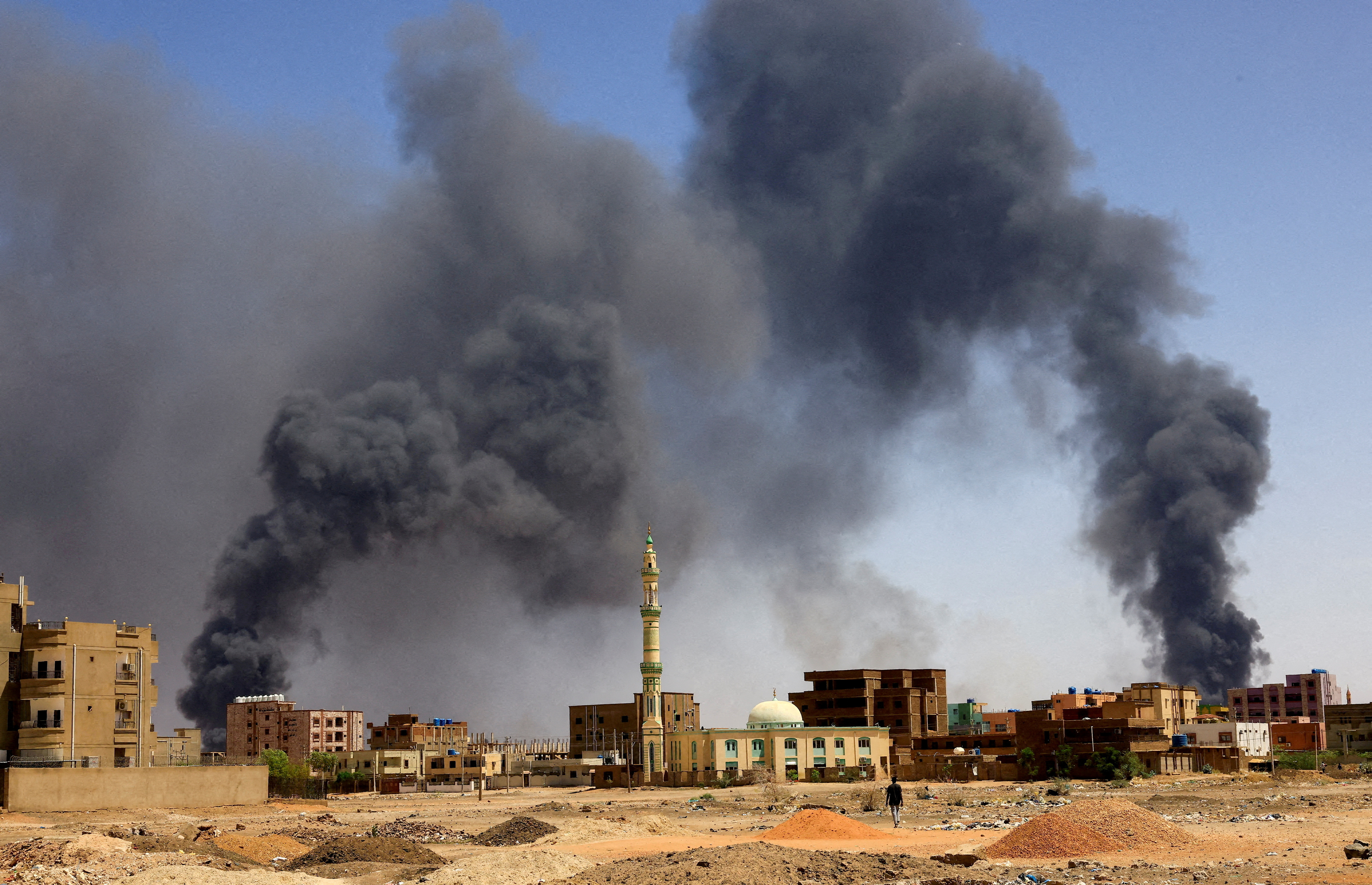 FILE PHOTO: A man walks while smoke rises above buildings after aerial bombardment, during clashes between the paramilitary Rapid Support Forces and the army in Khartoum North, Sudan, May 1, 2023. REUTERS/Mohamed Nureldin Abdallah
