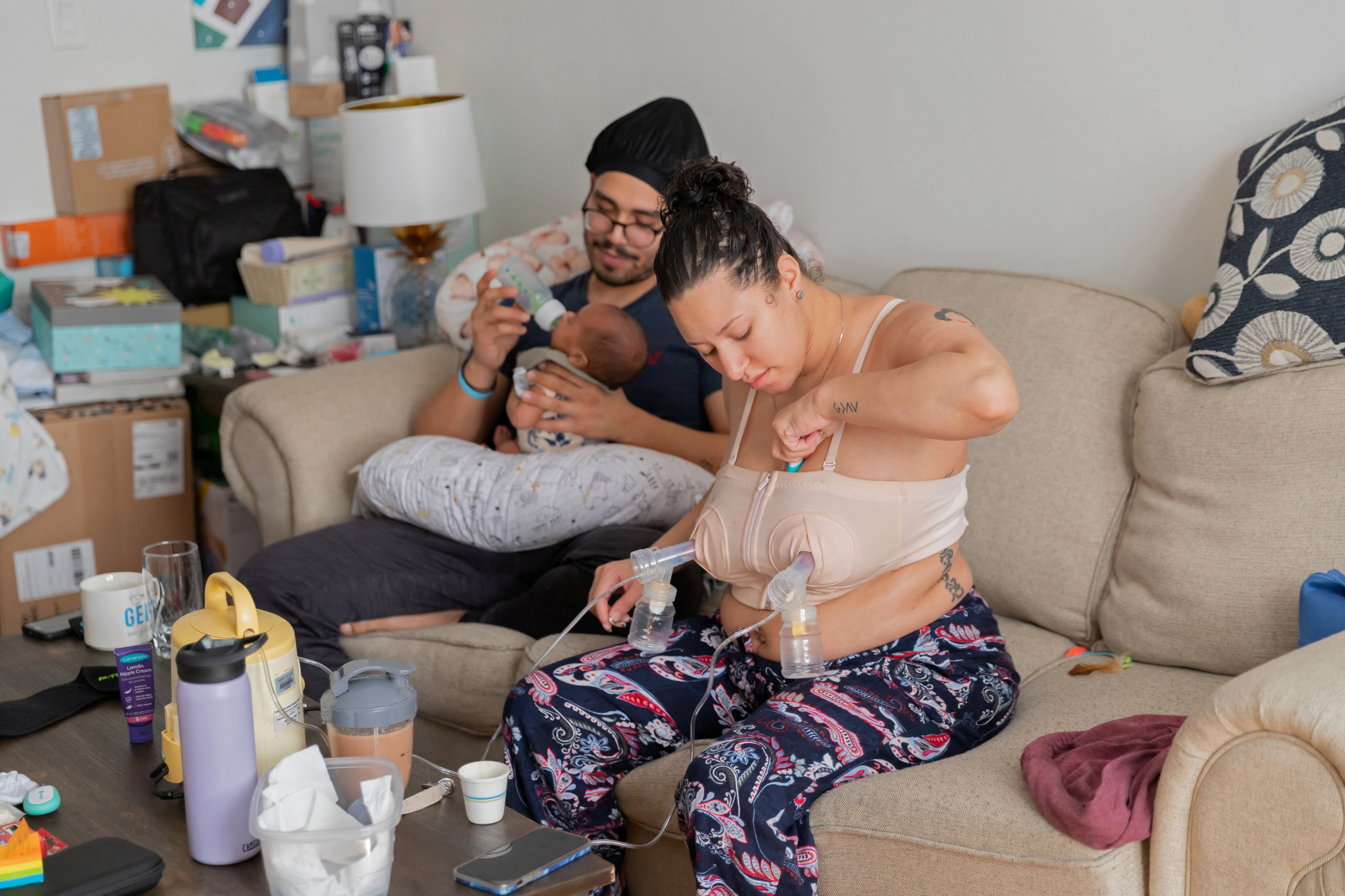Program manager Shariah Bottex, 30, pumps milk while her fiance, paramedic Jose Quinonez, 30, feeds their newborn son Kaiel in Flushing, New York, U.S., March 16, 2023. REUTERS/Joy Malone