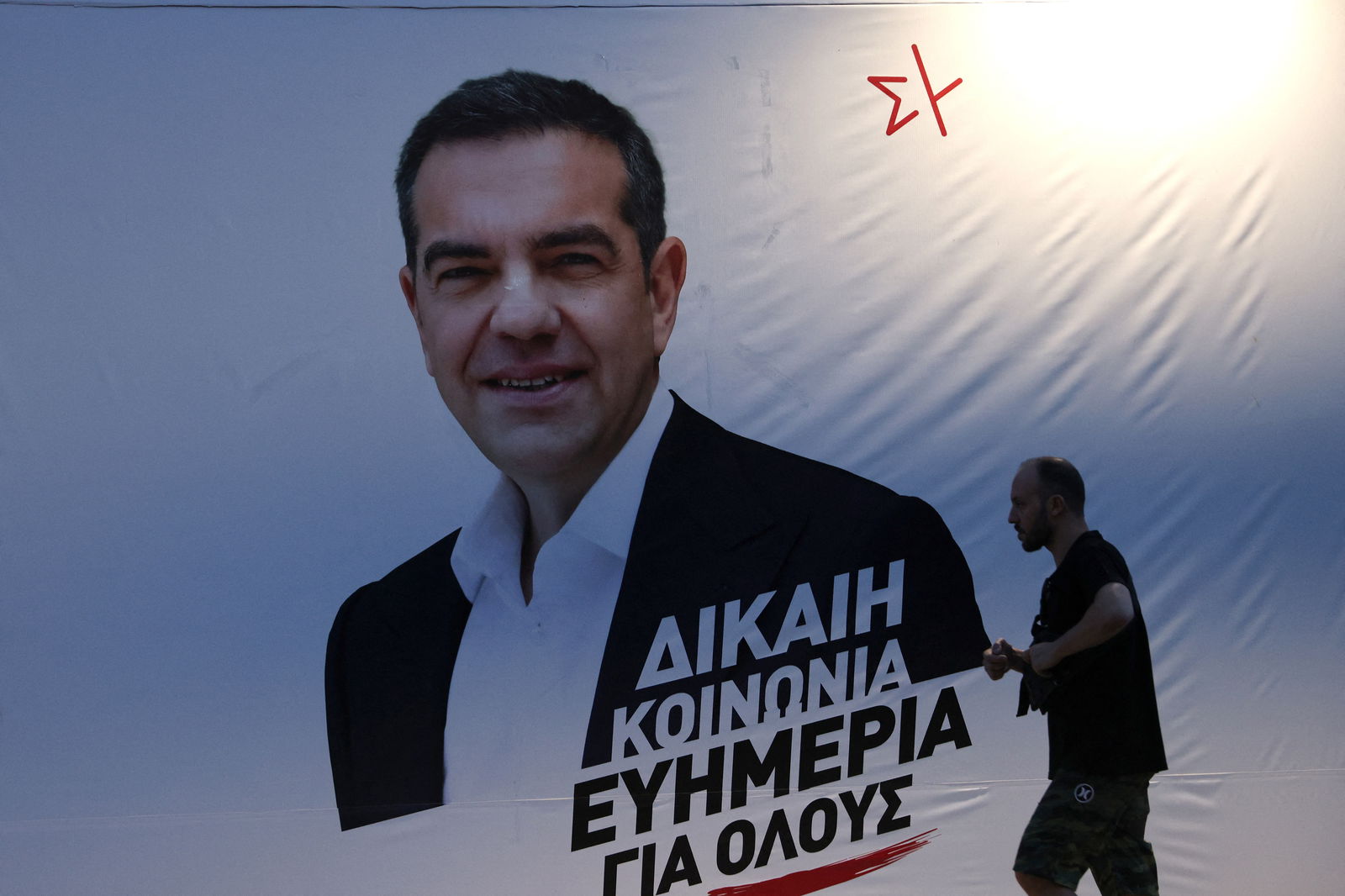 A man walks past election banner of Leftist Syriza party leader Alexis Tsipras ahead of the general election on Sunday, in Athens, Greece, June 24, 2023. REUTERS/Stoyan Nenov