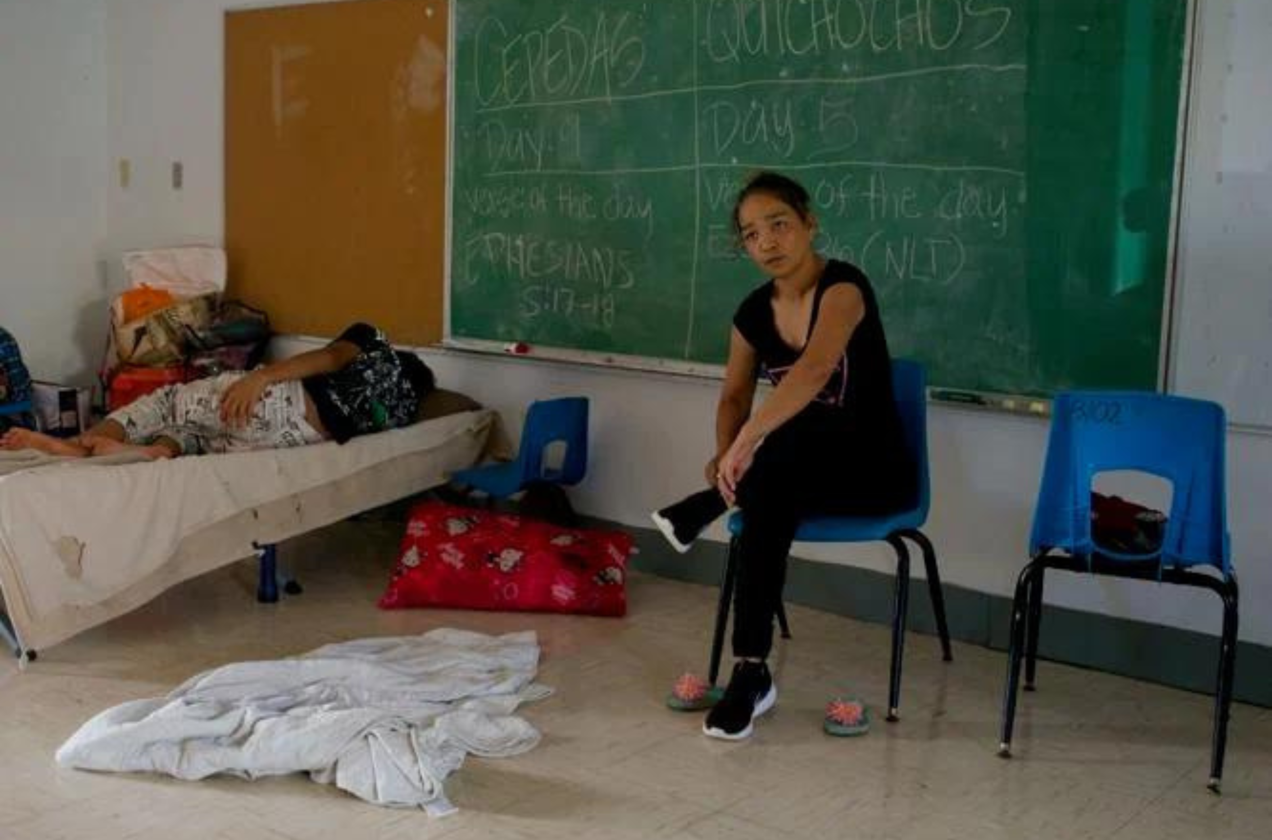 Lori Quichocho gets ready to leave for work Friday, June 2, 2023, while a family member sleeps soundly in a classroom at the Astumbo Elementary School emergency shelter.