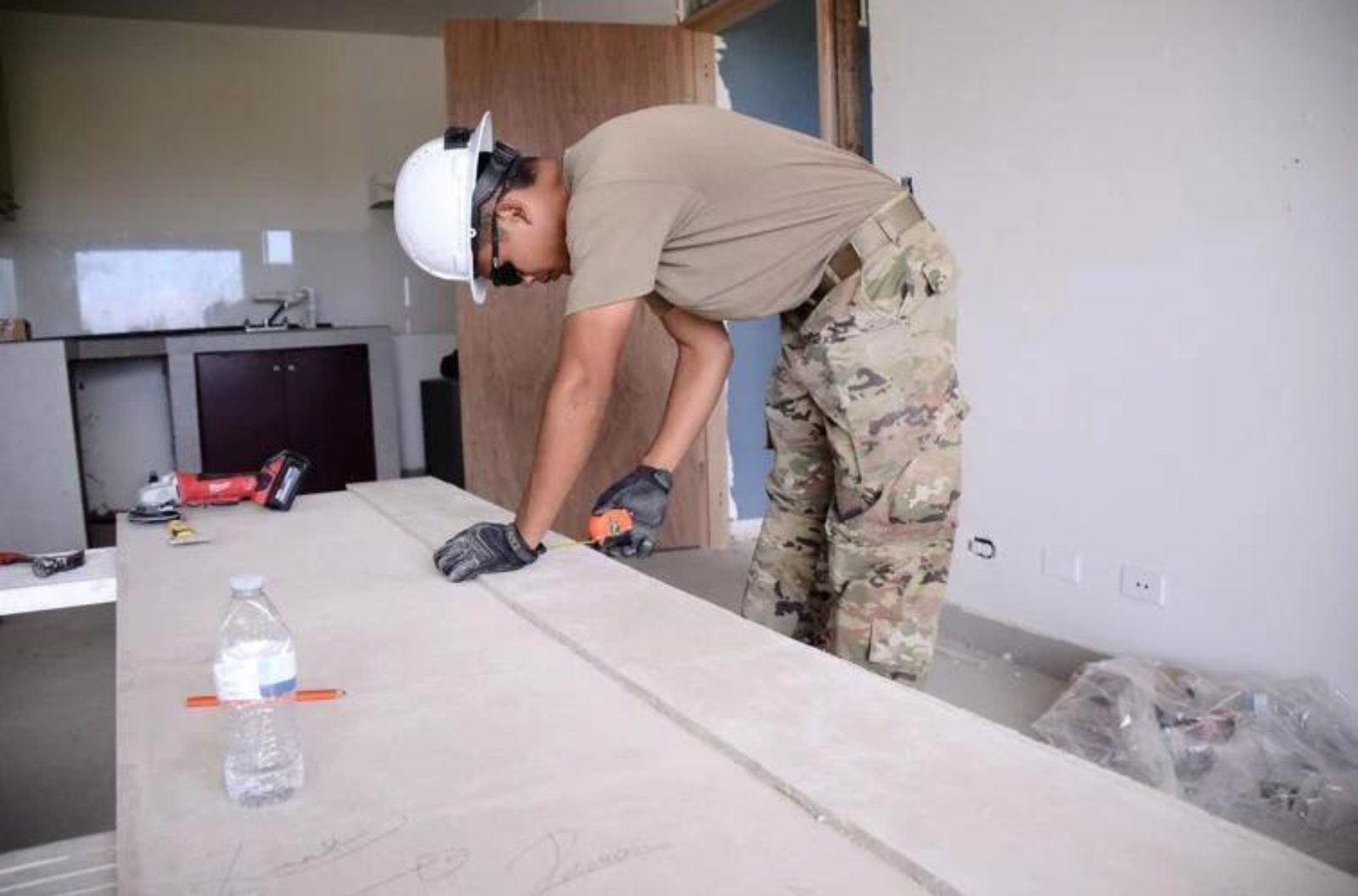Guam National Guard Spc. Gage Quitugua measures a panel of concrete wall to set up against a portion of a door frame. Quitugua and other Guard members were continuing renovation work Thursday, June 22, 2023, at a building set to become a homeless shelter in Anigua.