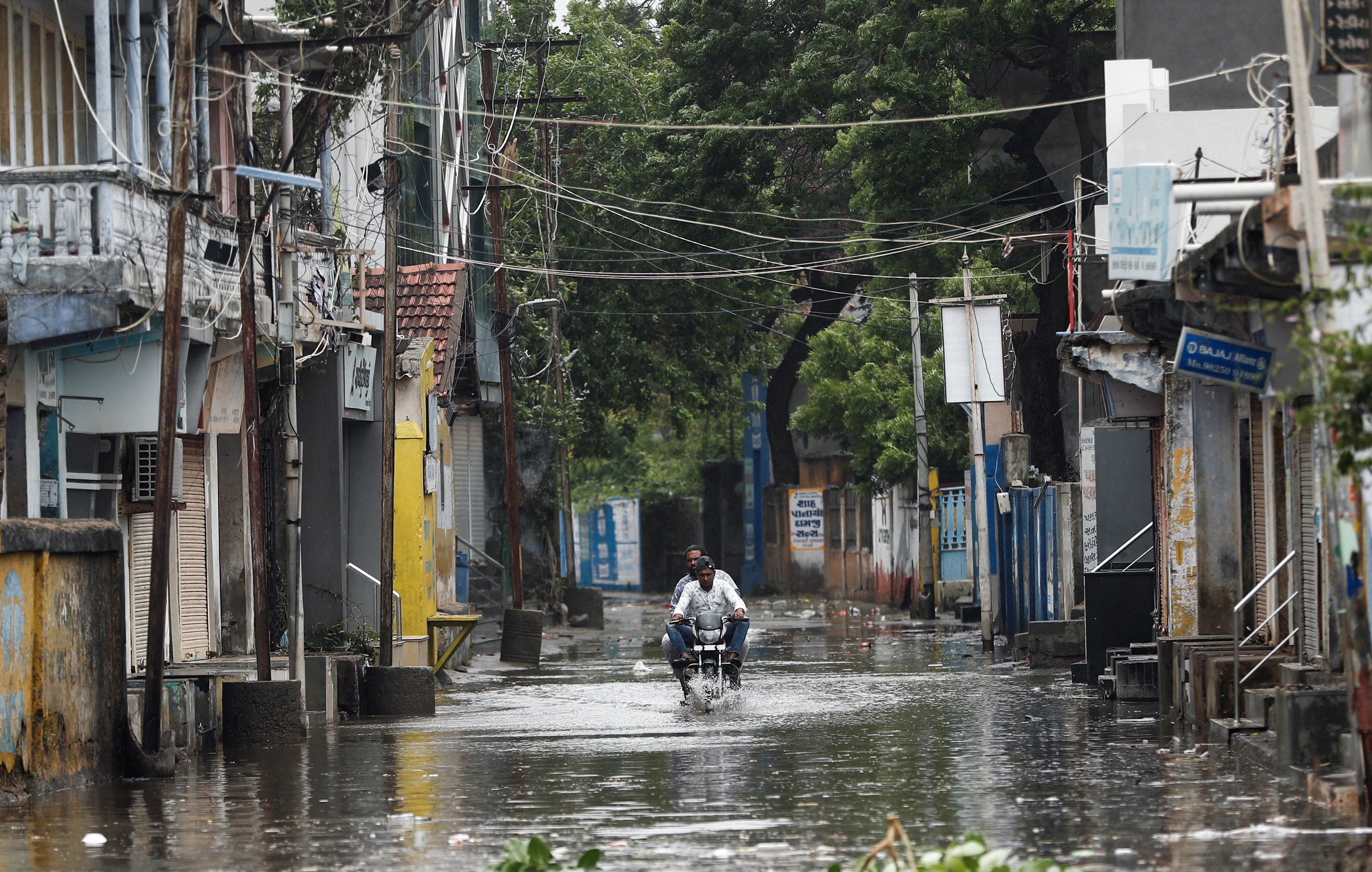 A man rides a motorcycle through a waterlogged street in Mandvi before the arrival of cyclone Biparjoy in the western state of Gujarat, India, June 15, 2023. REUTERS/Francis Mascarenhas