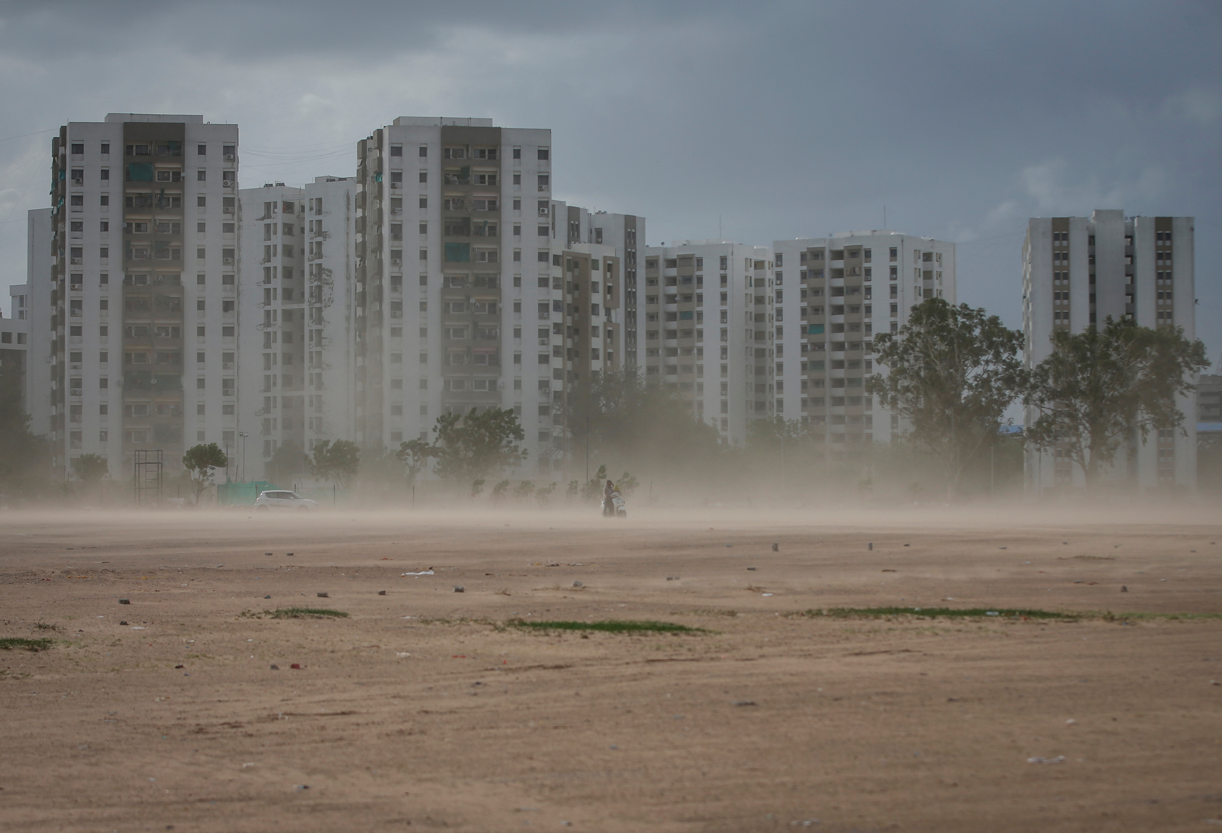 A couple rides a scooter amid dust due to strong wind, before the arrival of cyclonic storm Biparjoy, in Ahmedabad, India, June 15, 2023. REUTERS/Amit Dave