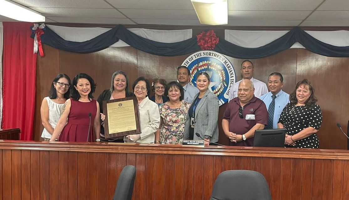 Consolaction C. Togawa, 4th left, holds the framed copy of Senate Resolution 23-4 as she poses for a photo with her family, Senate President Edith Deleon Guerrero and other senators on Friday last week.