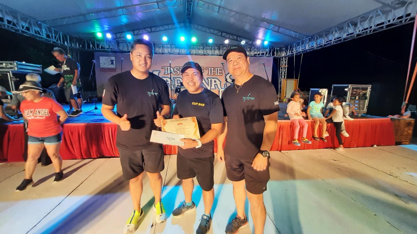 On behalf of Korean Cup Bap, Dante Conlu, center, receives 2nd place on June 24, 2023, in the booth decorating contest at the 24th Annual Taste of the Marianas International Food Festival & Beer Garden, at Garapan Fishing Base in Saipan. From left, Marianas Visitors Authority Managing Director Christopher A. Concepcion, Conlu, and MVA Community Projects Manager Martin Duenas.